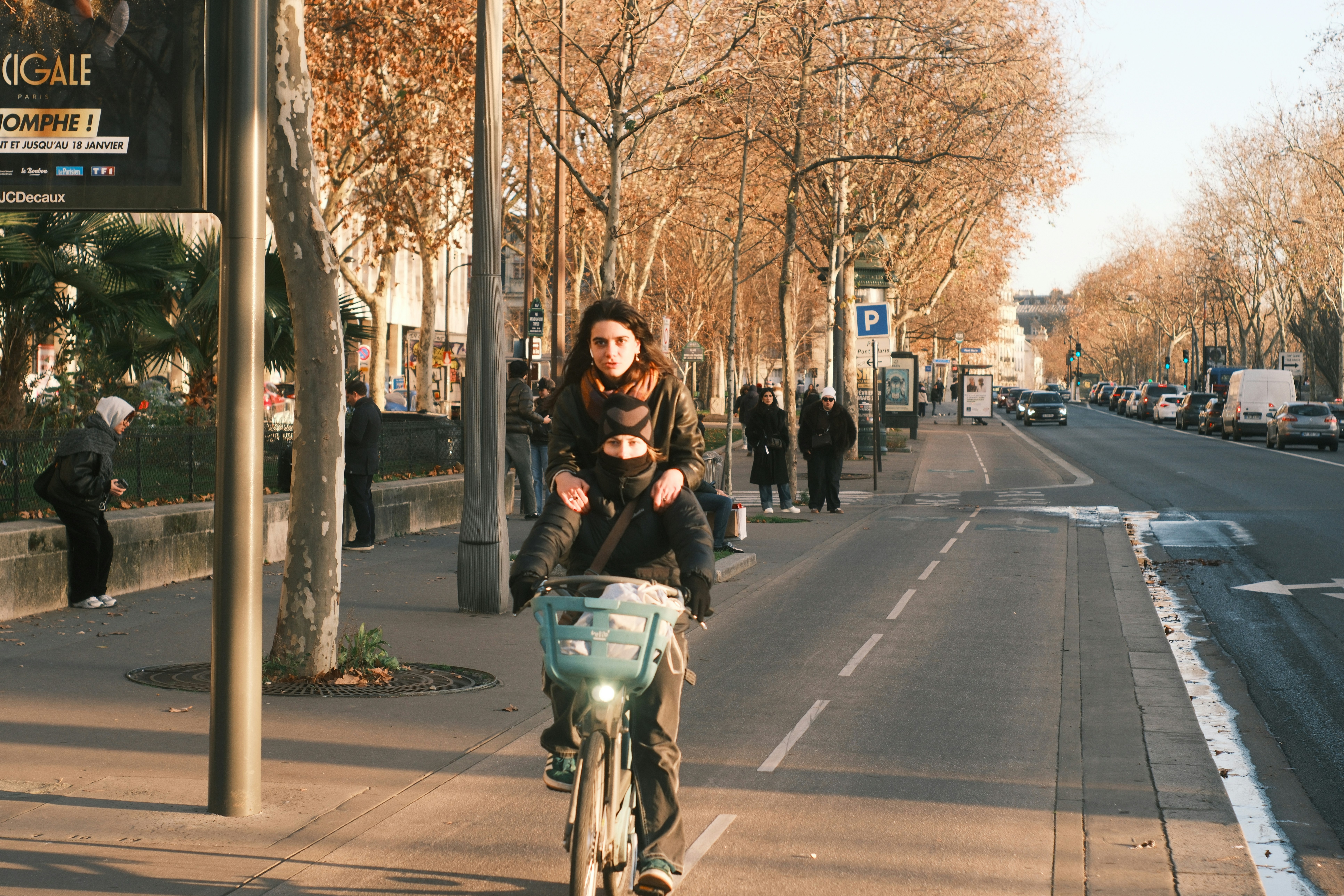 Woman riding bicycle with child in carrier.