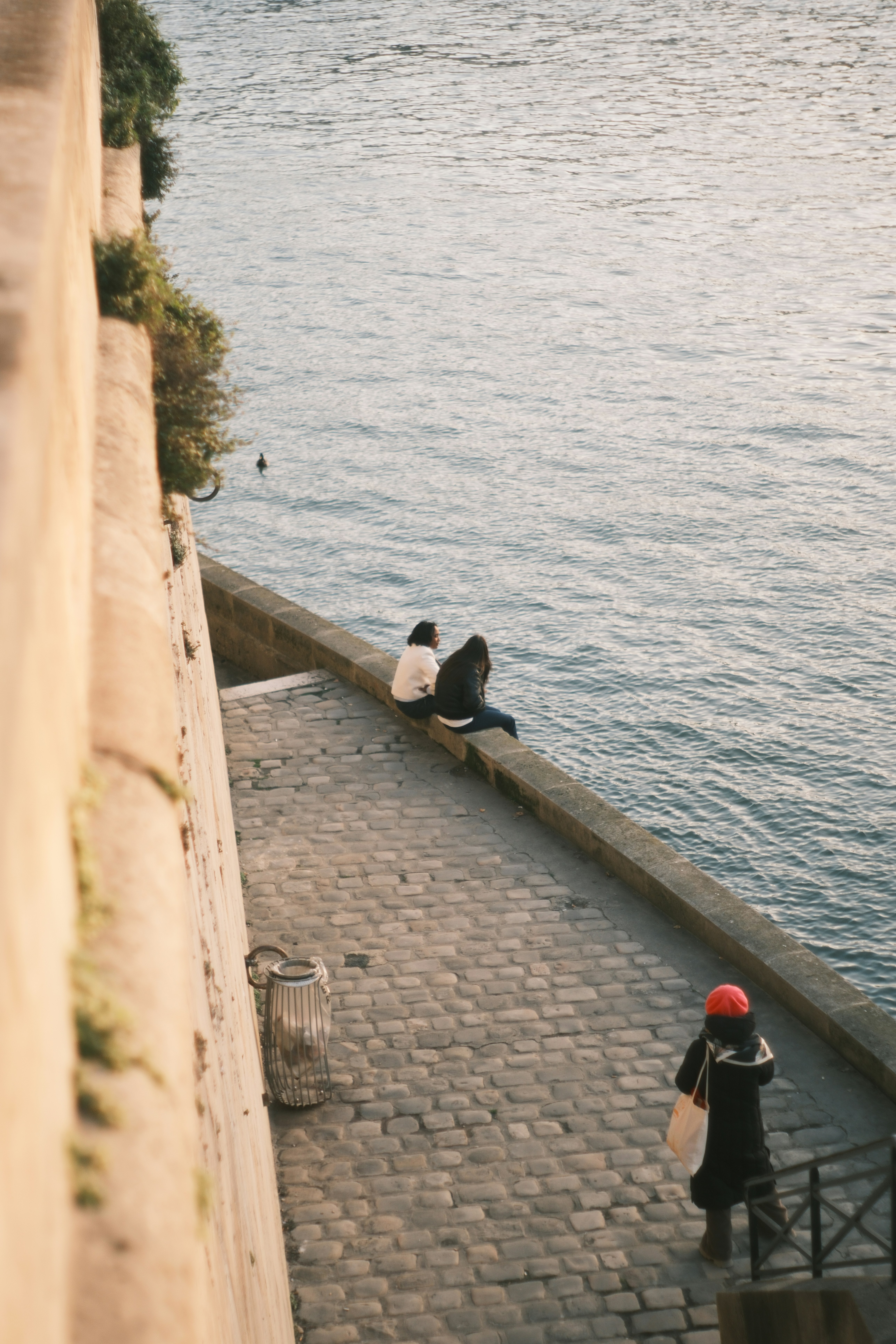 Two people sit by the water's edge