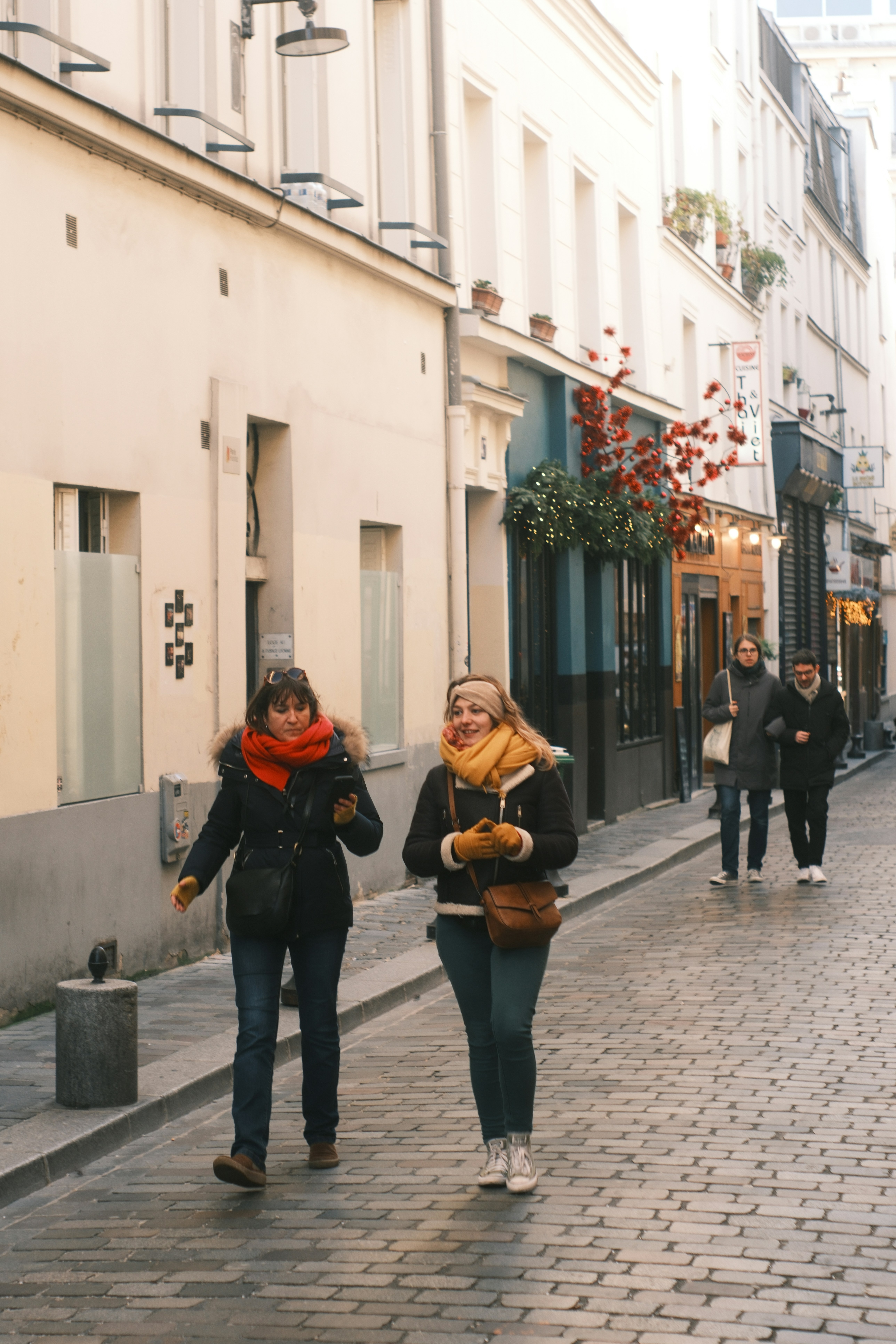 Two women walk down a cobblestone street in paris.