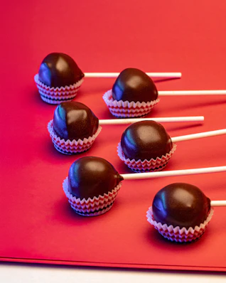 Six chocolate cake pops on red background