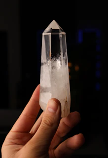 Hand holding a clear quartz crystal point