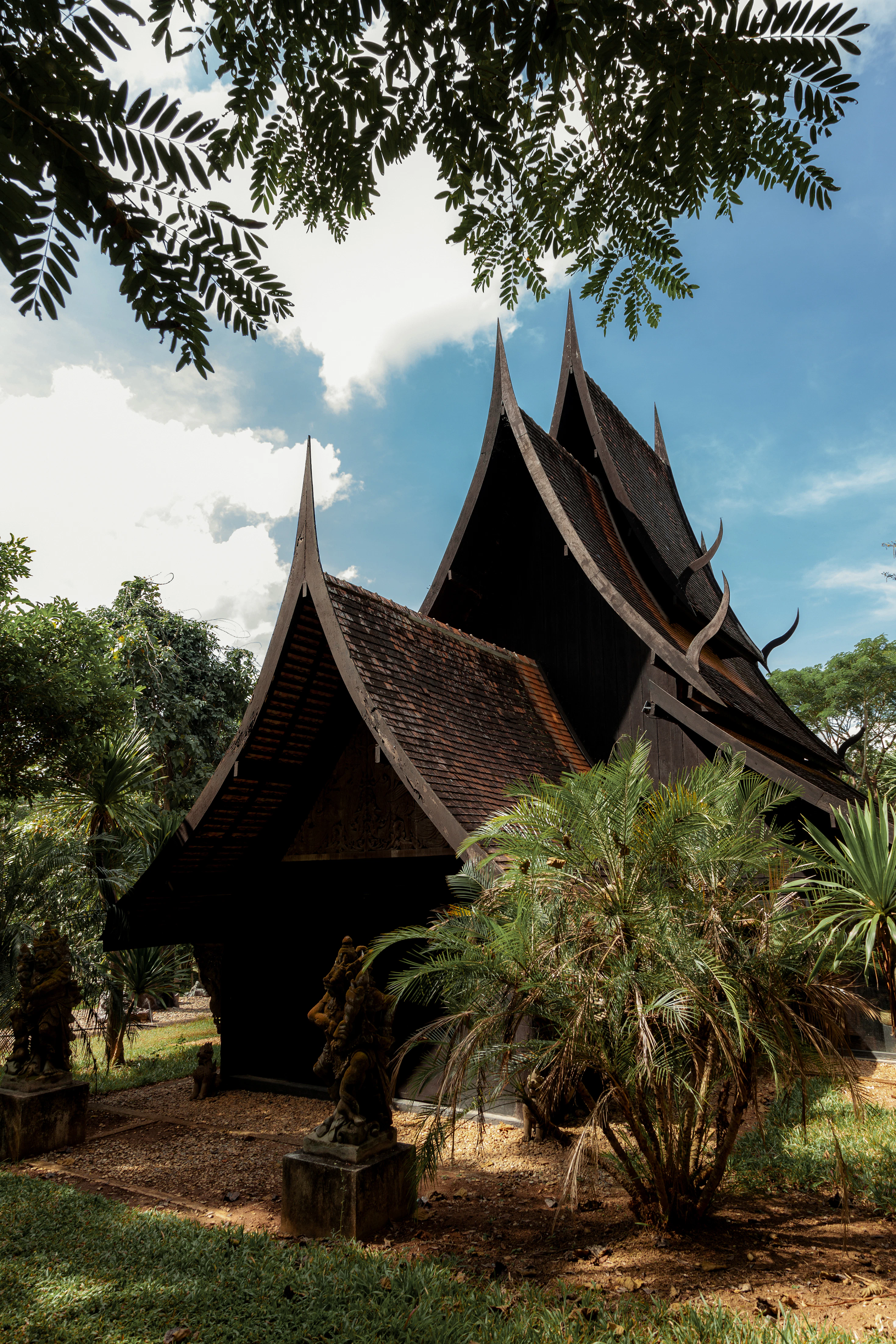 Dunkles Teakholzhaus mit geschwungenem Dach im Baan Dam Museum bei Chiang Rai