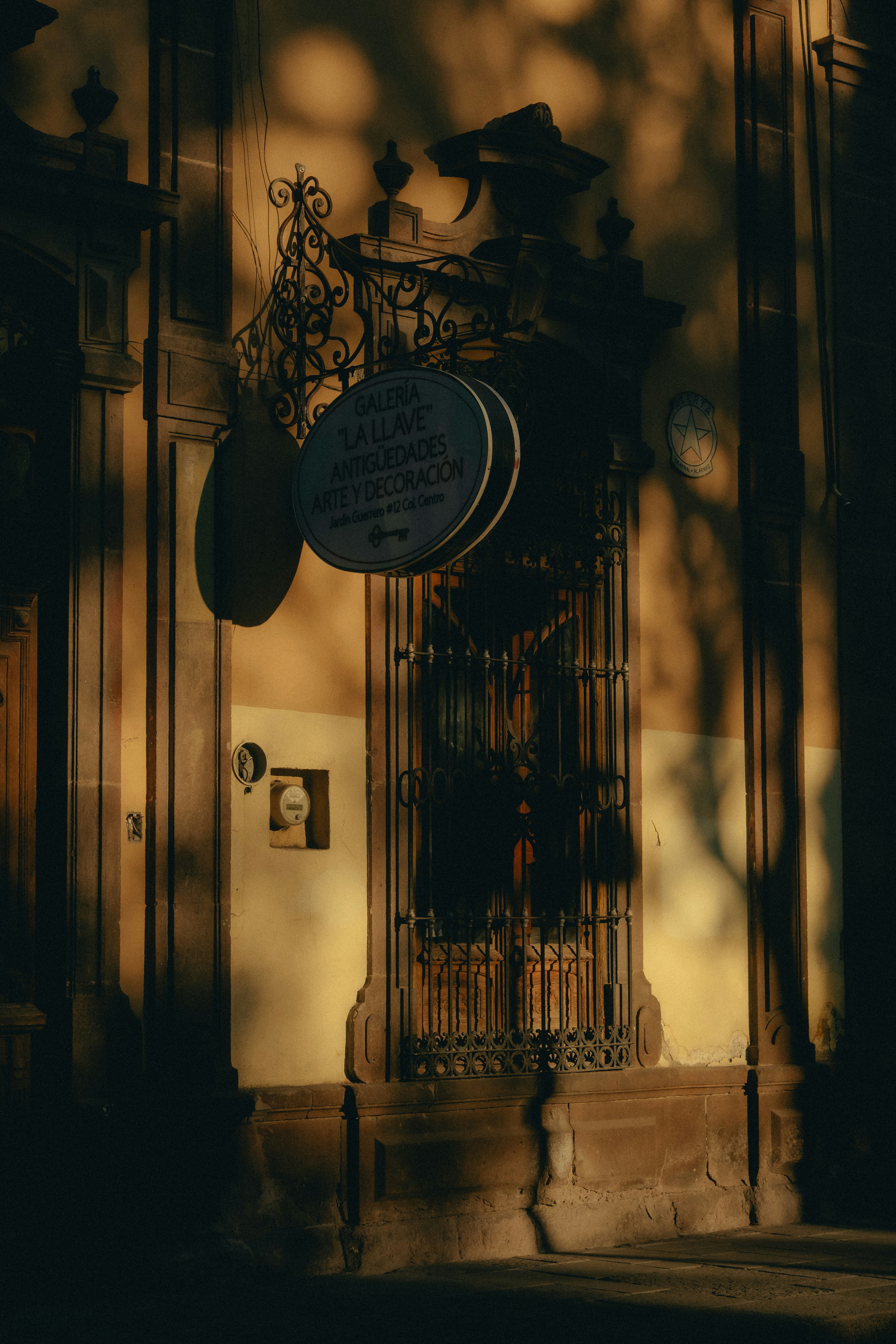 Ornate building facade with circular sign and shadows.