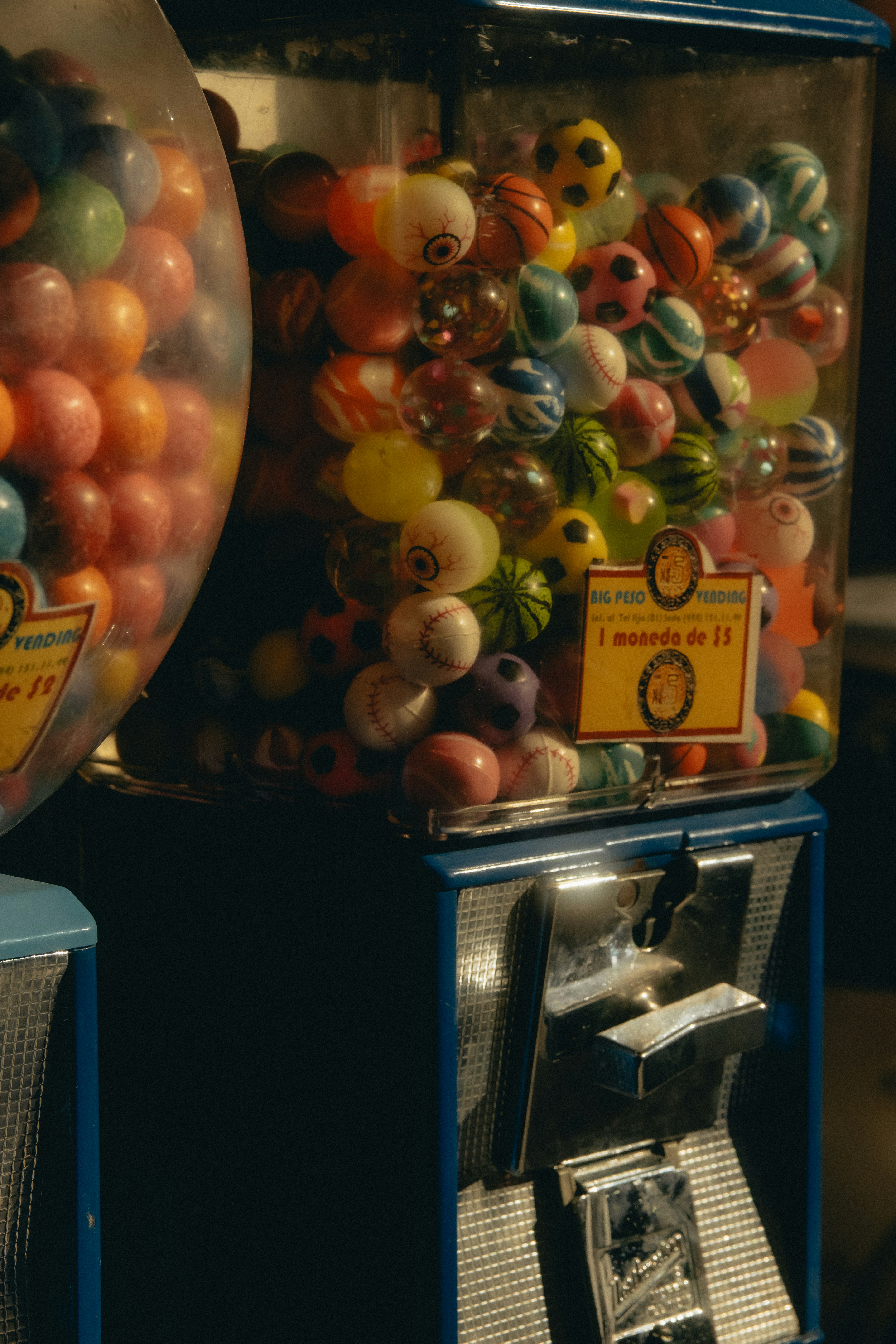 Two vintage gumball machines filled with colorful gumballs.