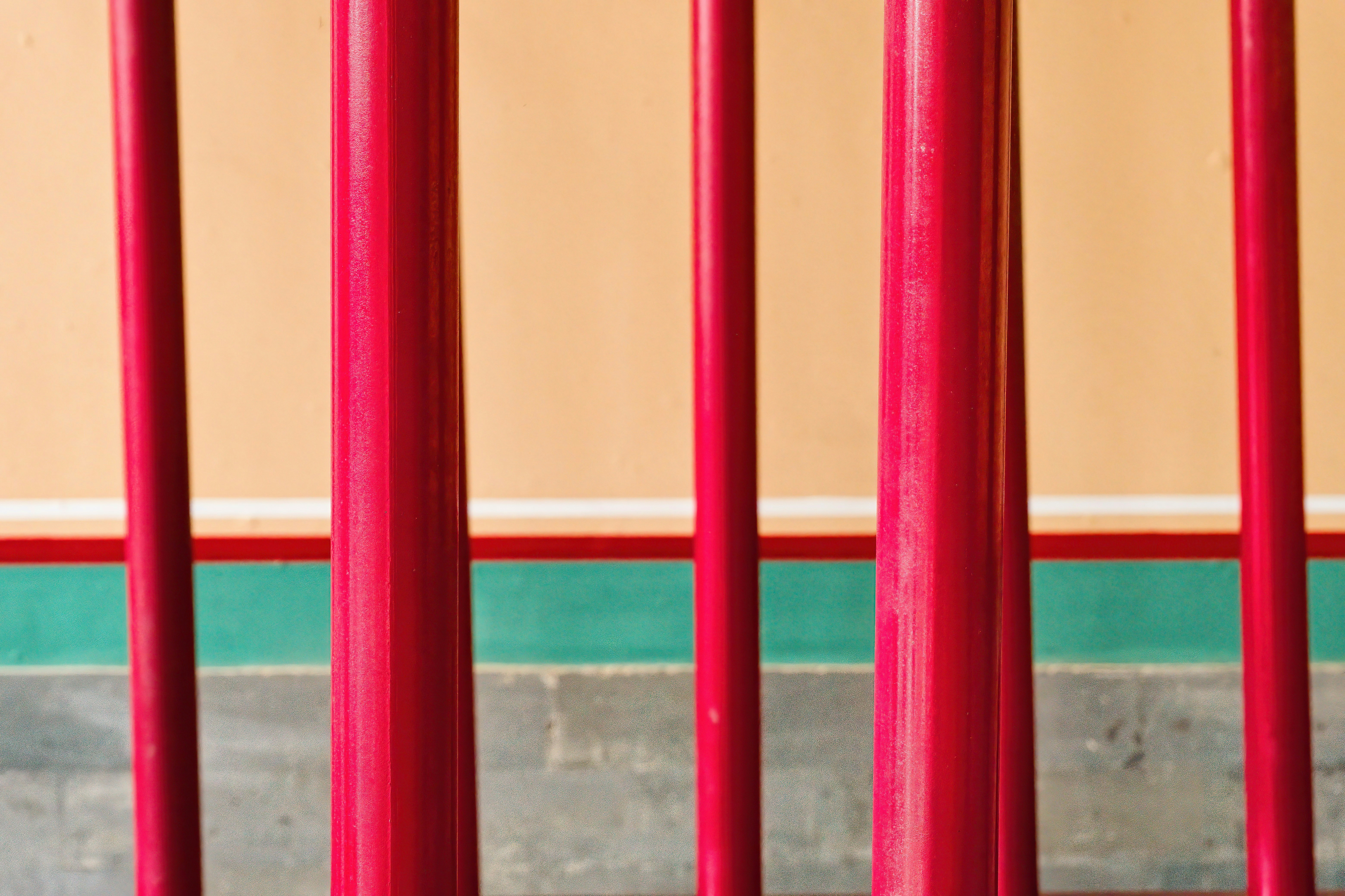 Postes verticales rojos sobre un fondo melocotón y verde azulado