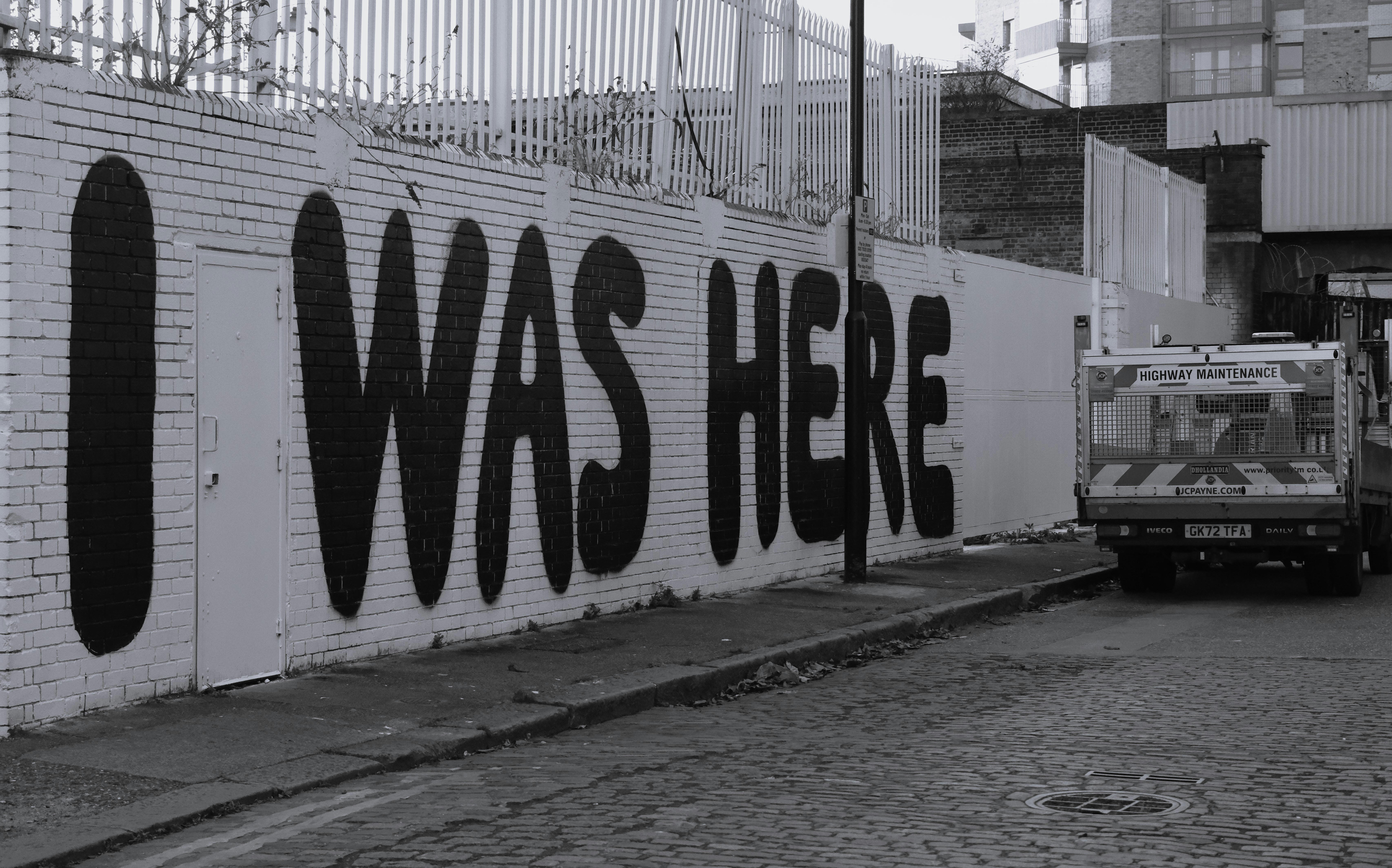 Graffiti scritto "ero qui" su un muro di mattoni.