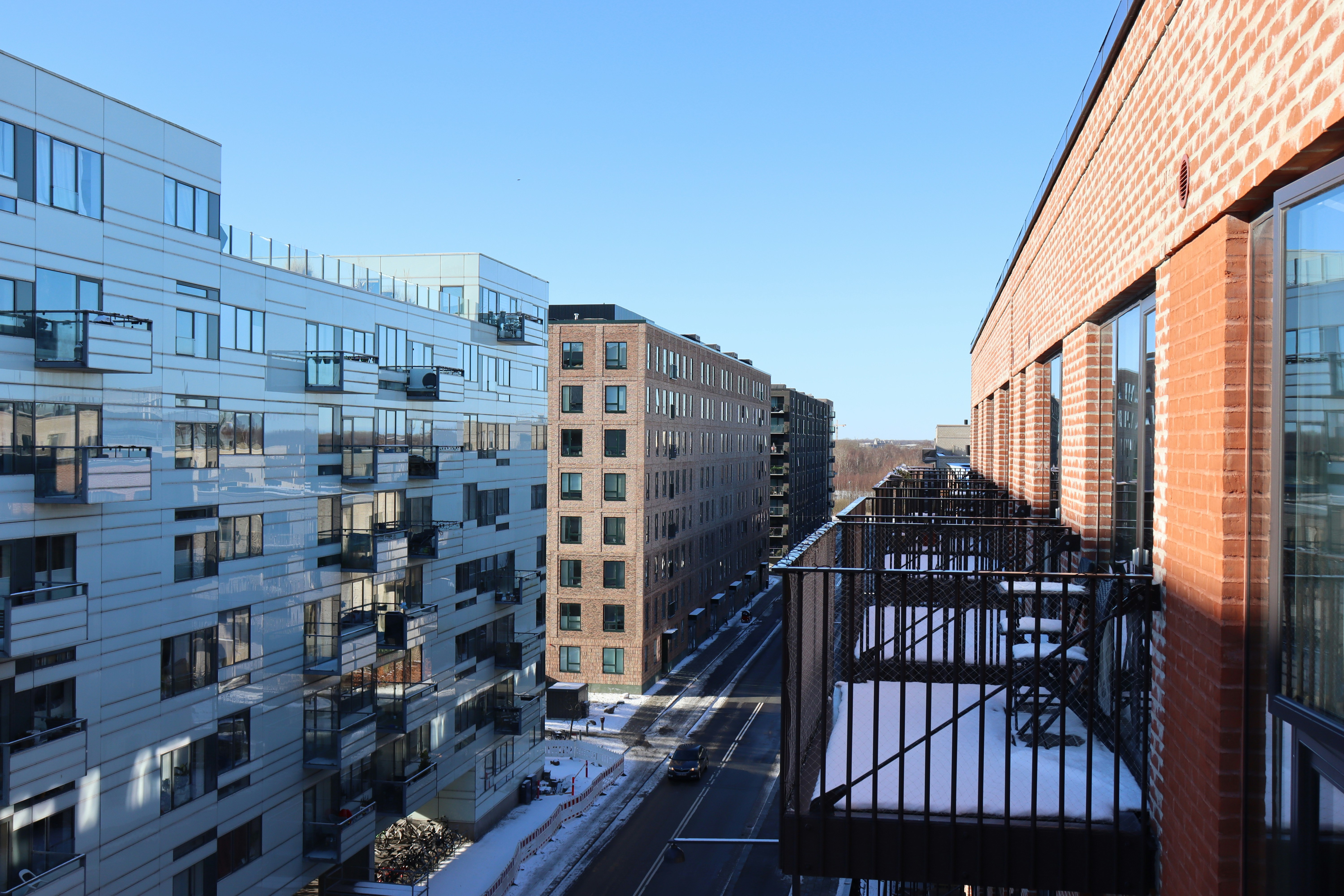 Modern apartment buildings line a snowy city street.