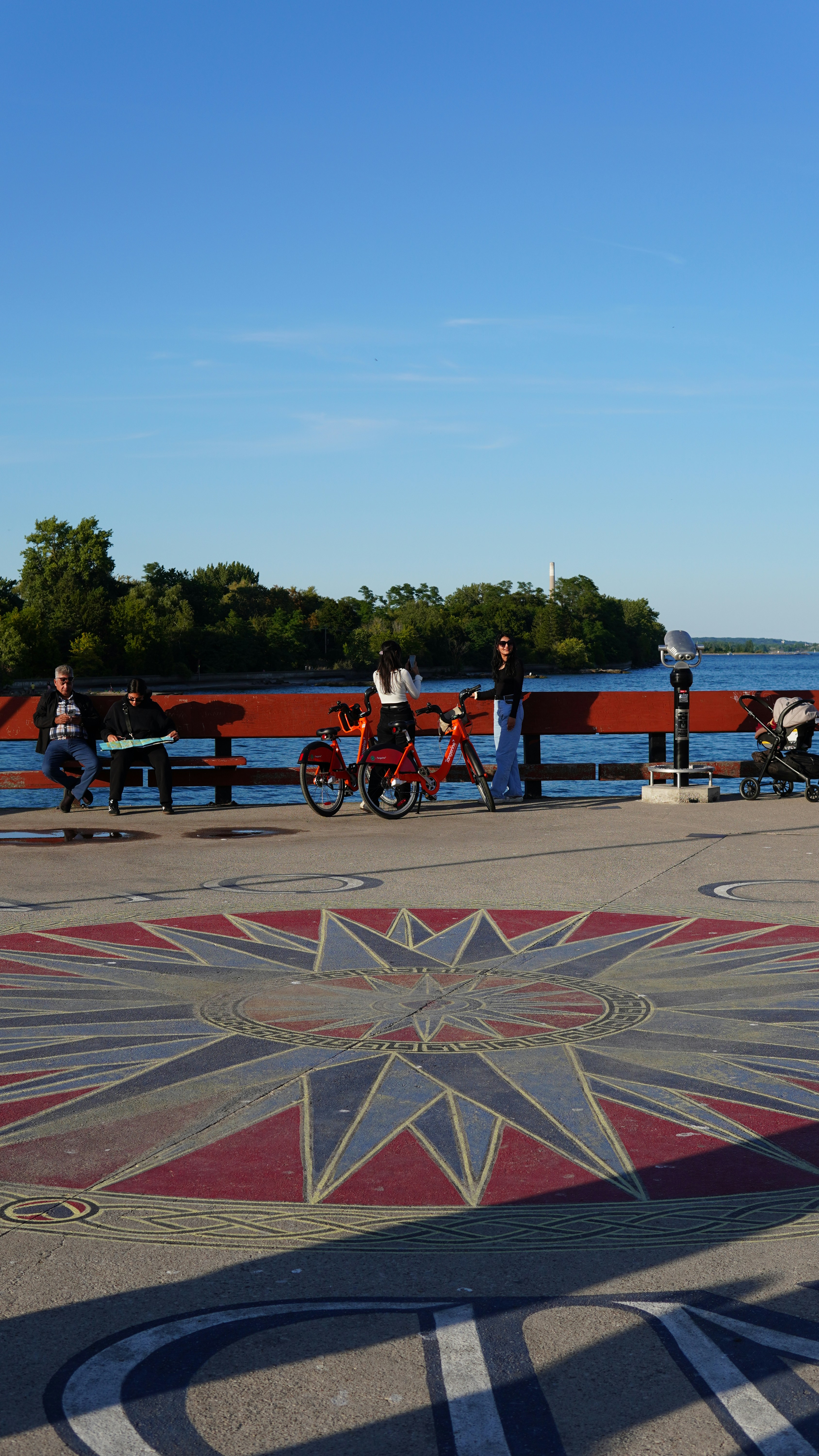 People and bikes by a waterfront compass rose design.