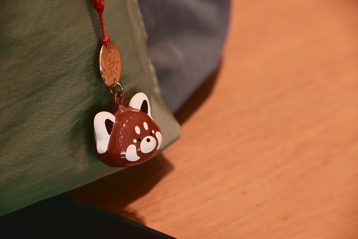 A cute character charm clipped to the strap of a backpack