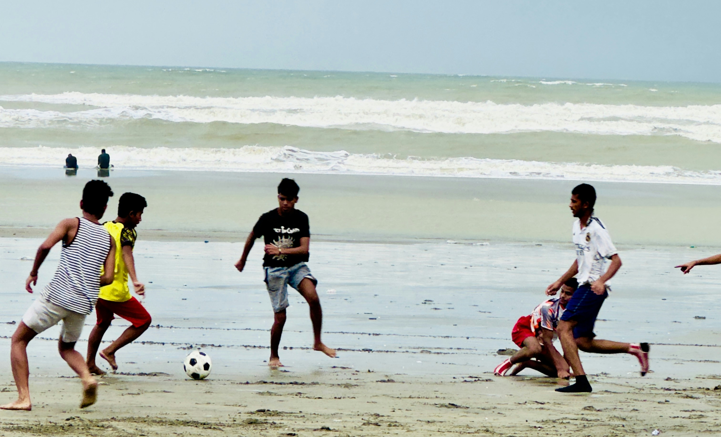 Giovani uomini che giocano a calcio su una spiaggia sabbiosa.
