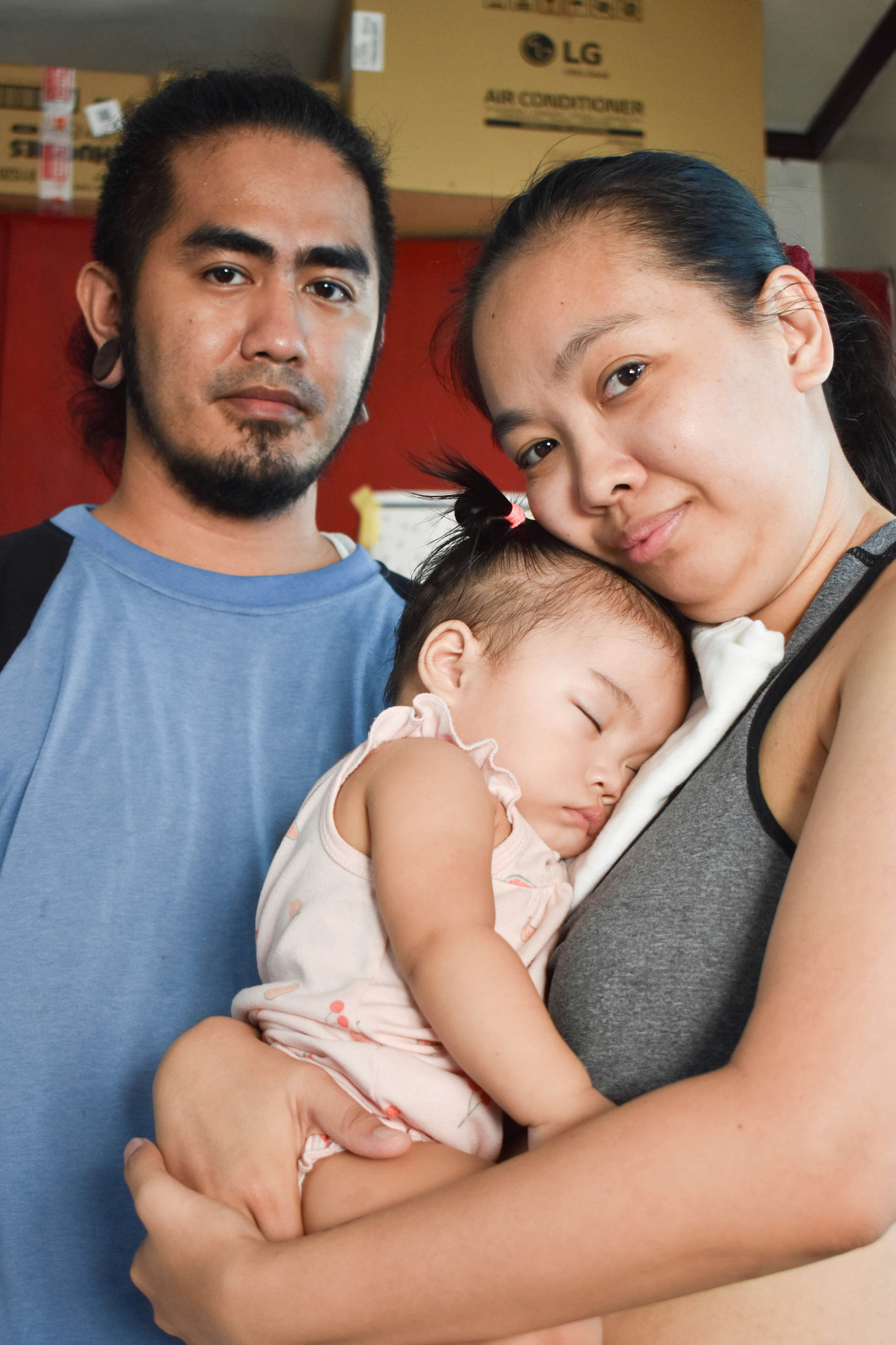 Una madre sostiene a su bebé dormido mientras el padre está a su lado.