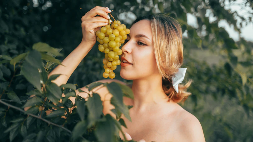 Woman holding a bunch of green grapes outdoors