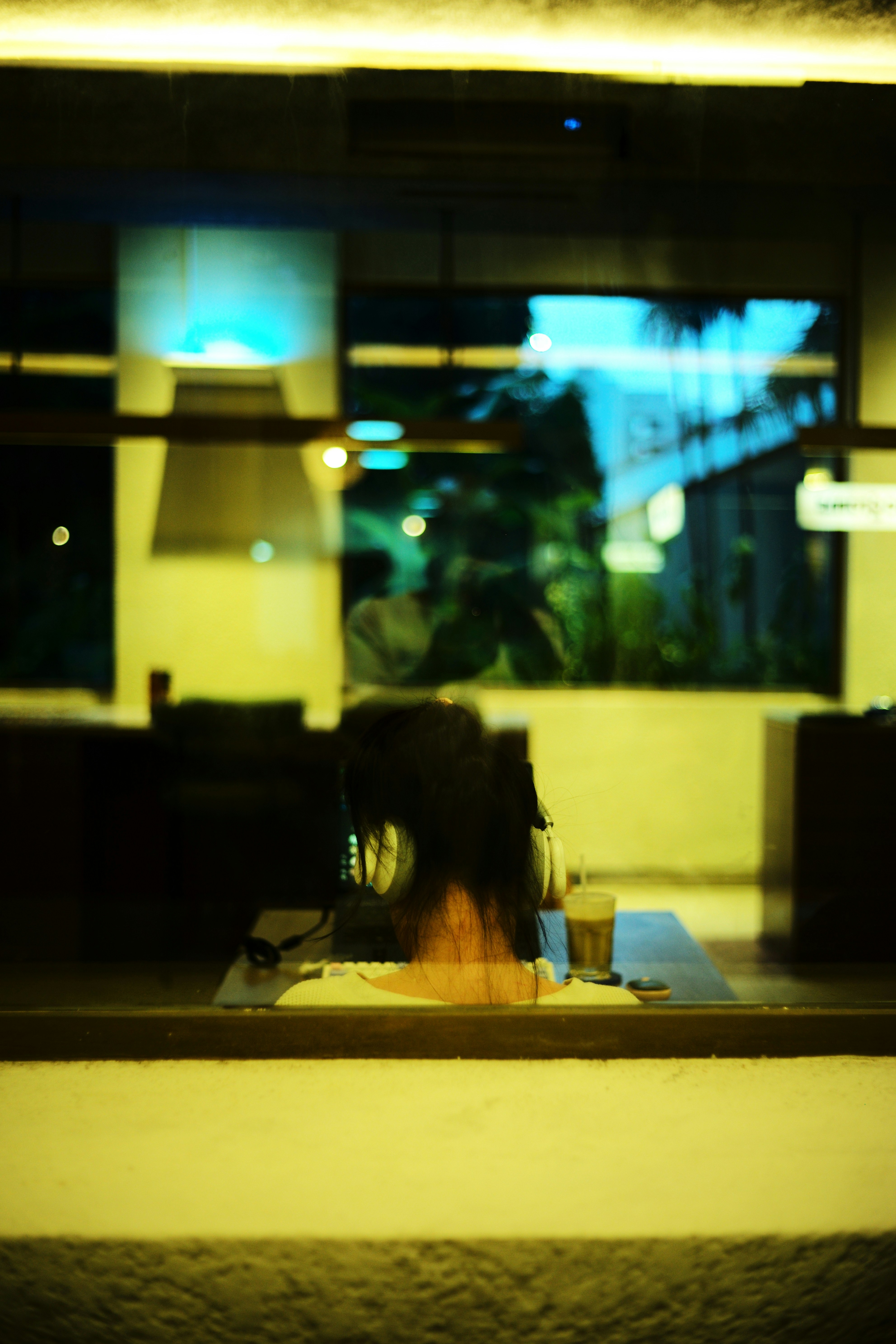 Person reflected in window with drink on table