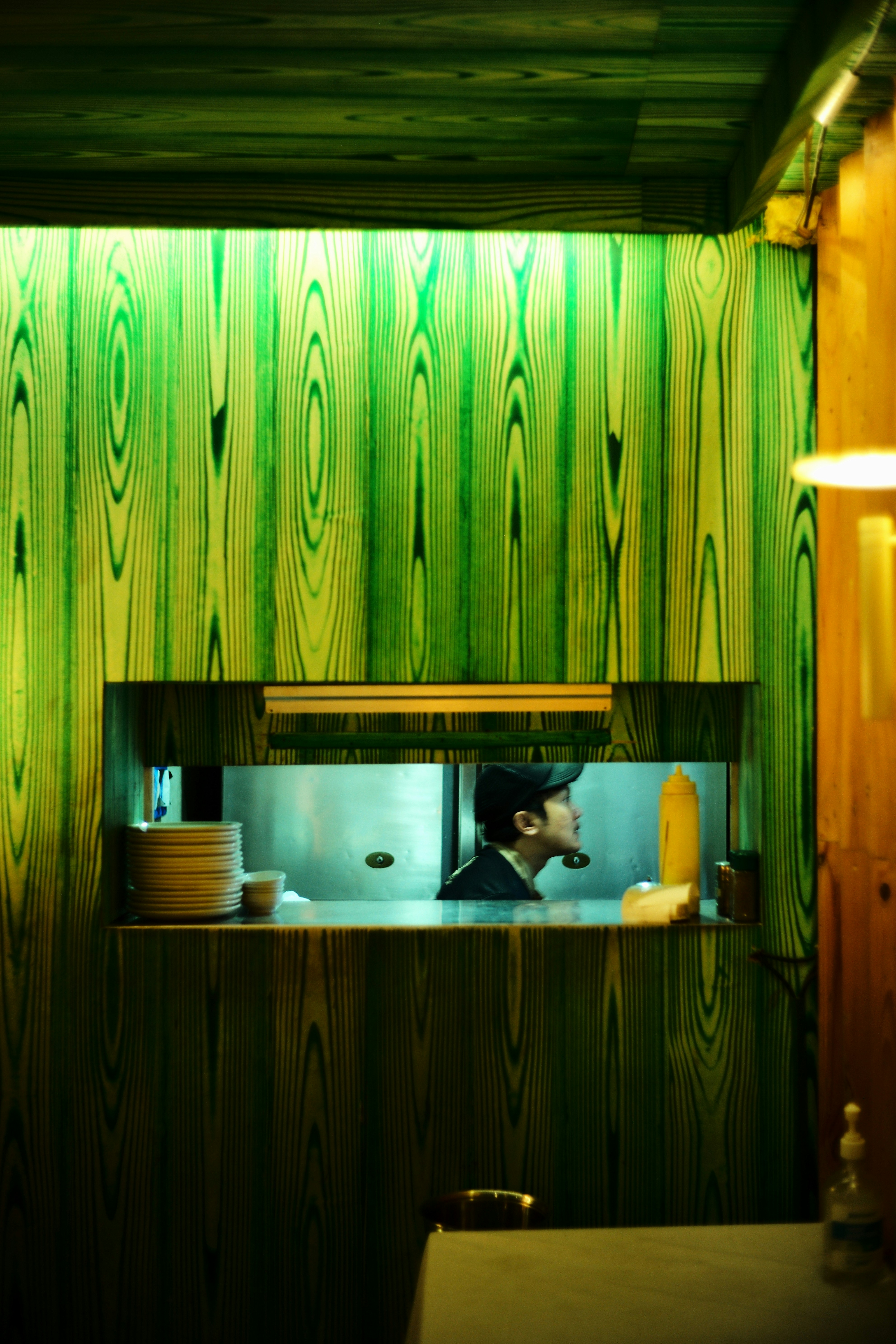 Man in kitchen behind green wooden wall