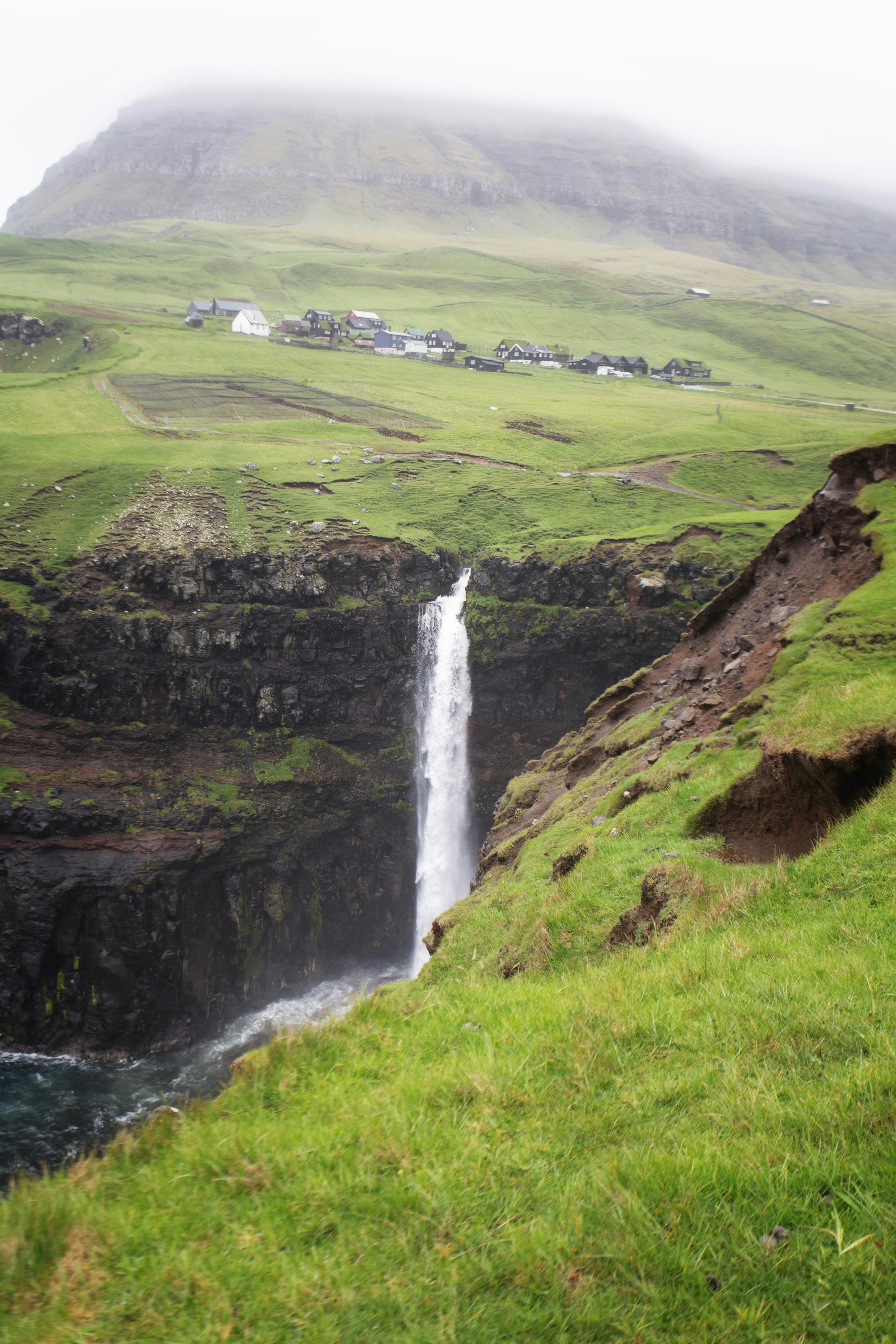 Wasserfall, der eine Klippe in der Nähe eines Dorfes hinunterstürzt
