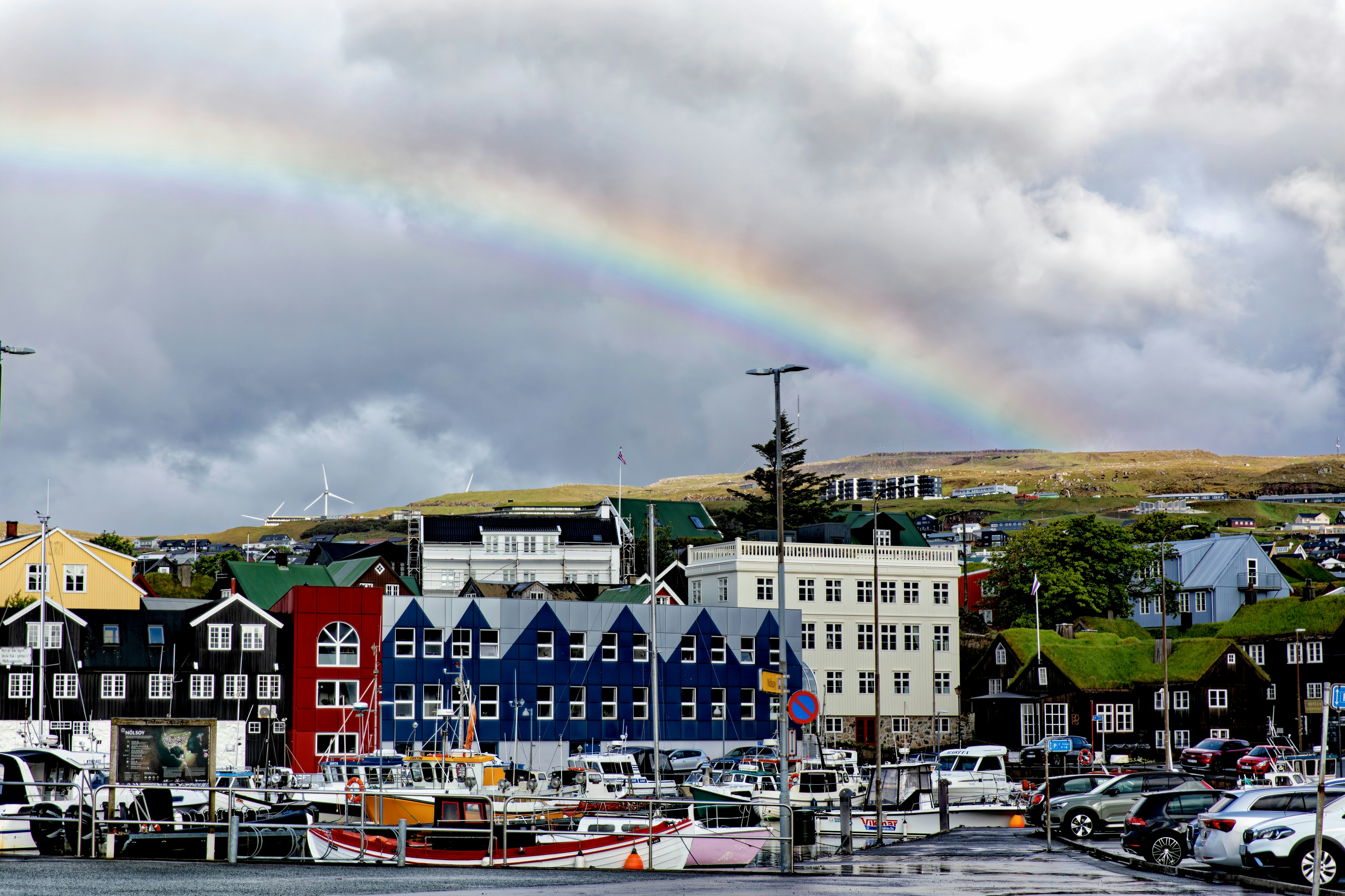 Regenbogen über bunten Gebäuden und Hafen mit Booten.