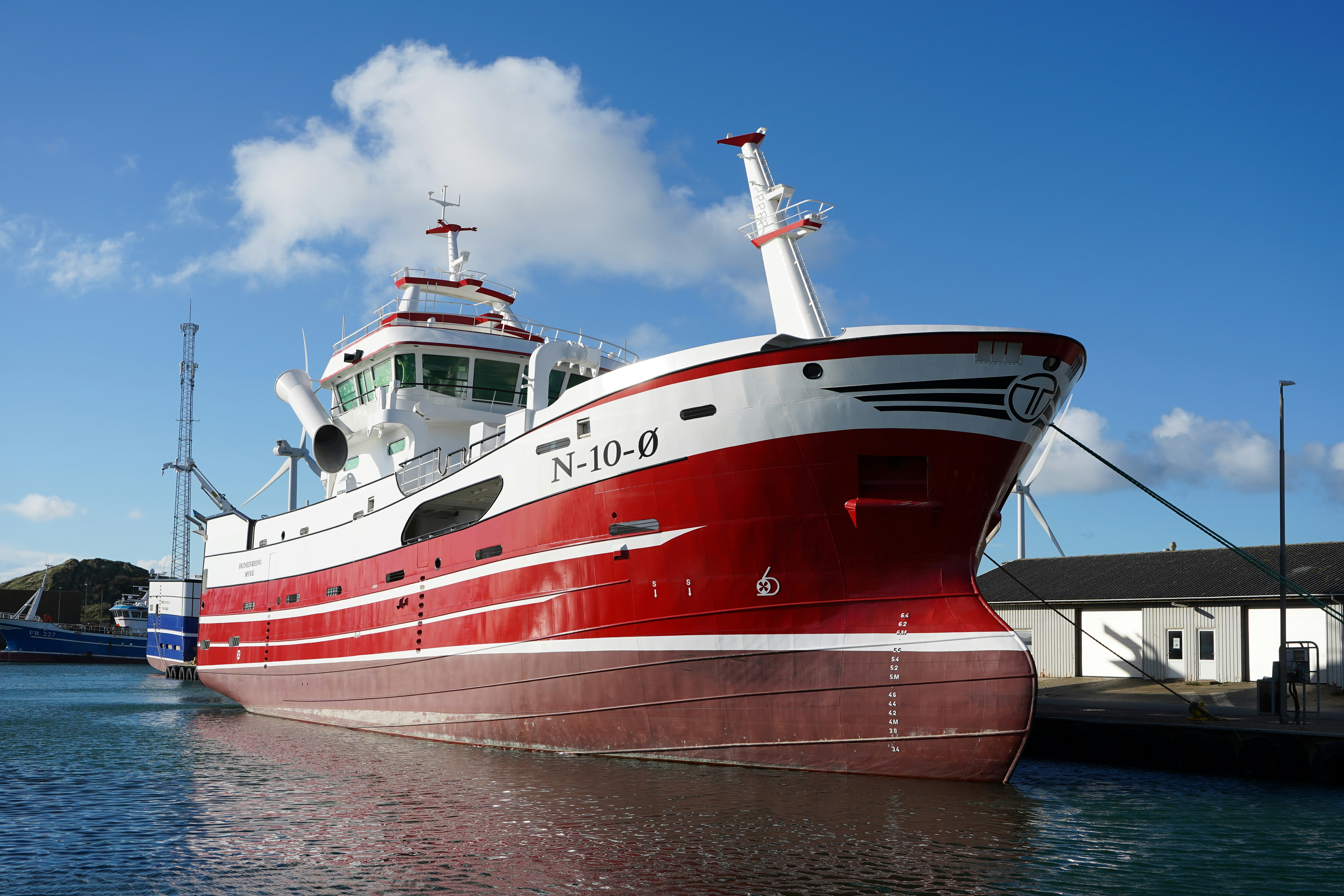 A red and white fishing trawler docked in a harbor.