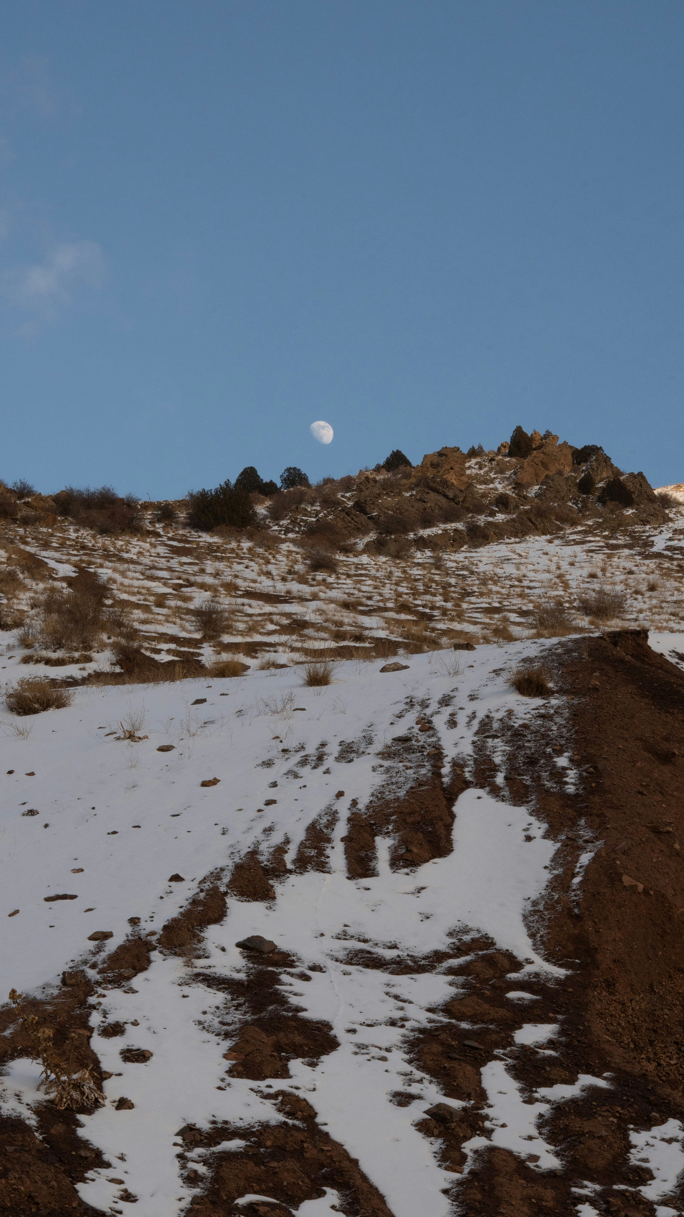 雪に覆われた山の景色に見える月。