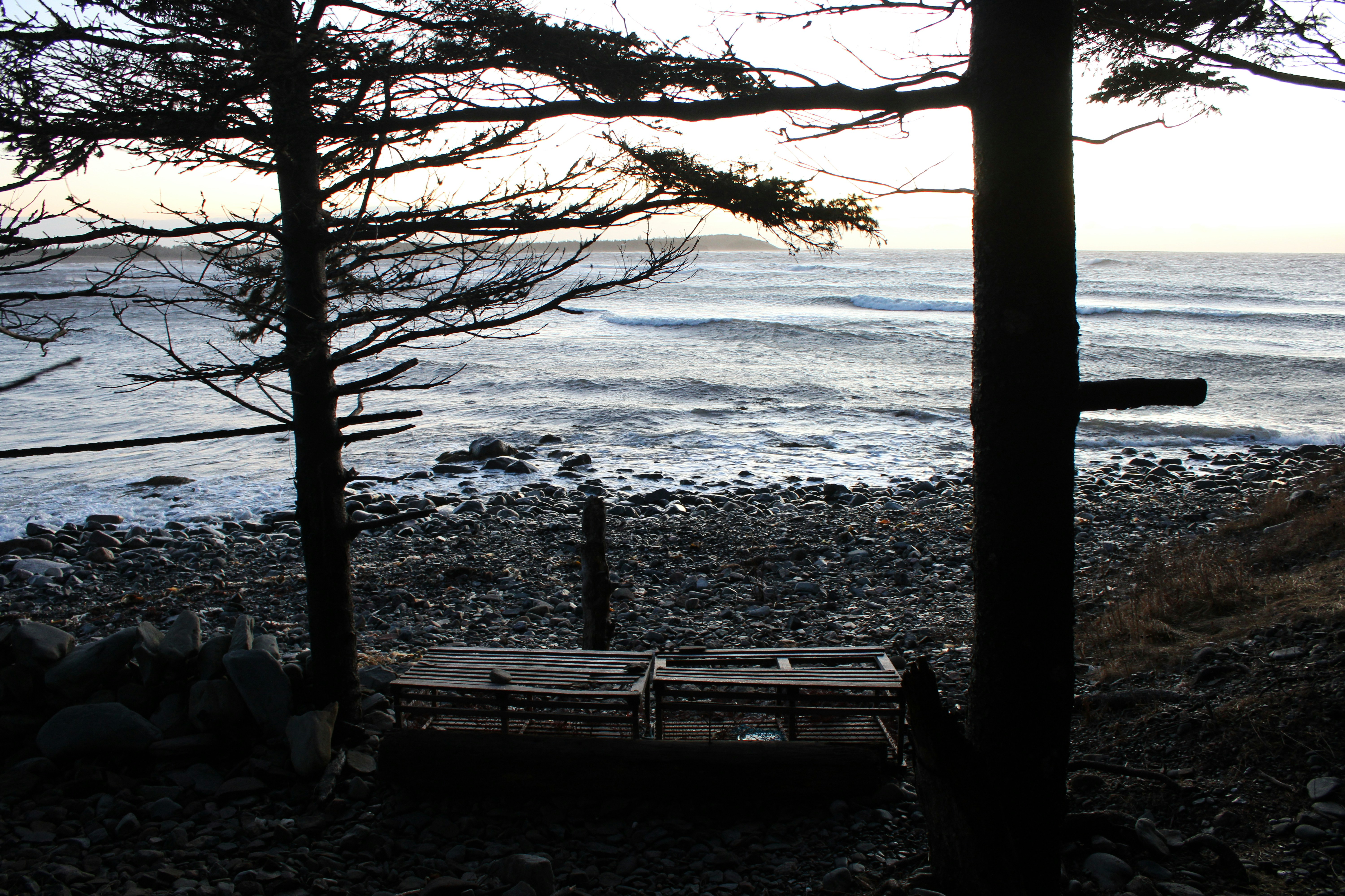 Two lobster traps on a rocky shore near ocean.