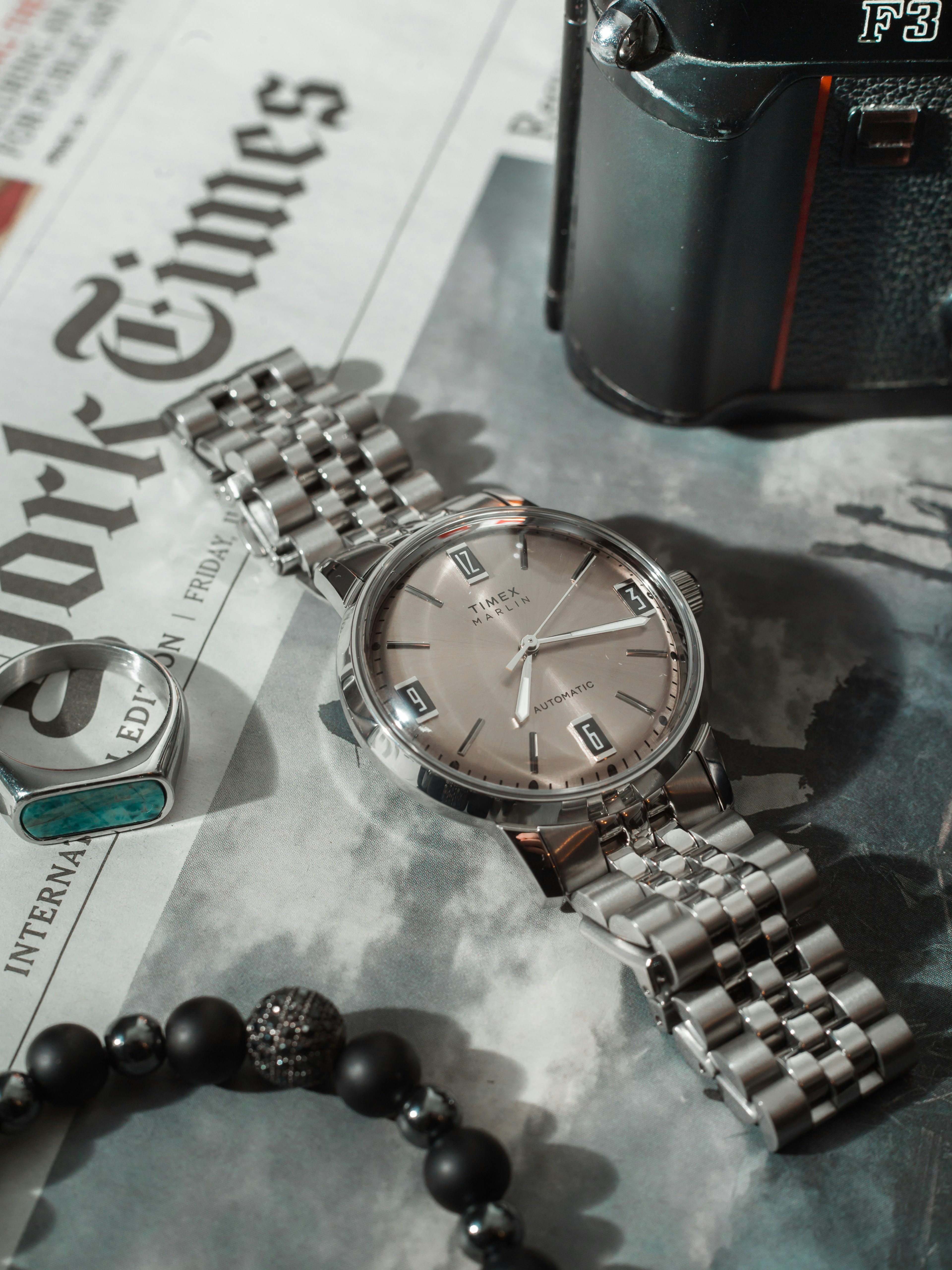 Jam tangan vintage di koran dengan perhiasan dan kamera