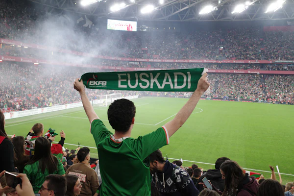 A fan holding up a scarf in a packed stadium crowd