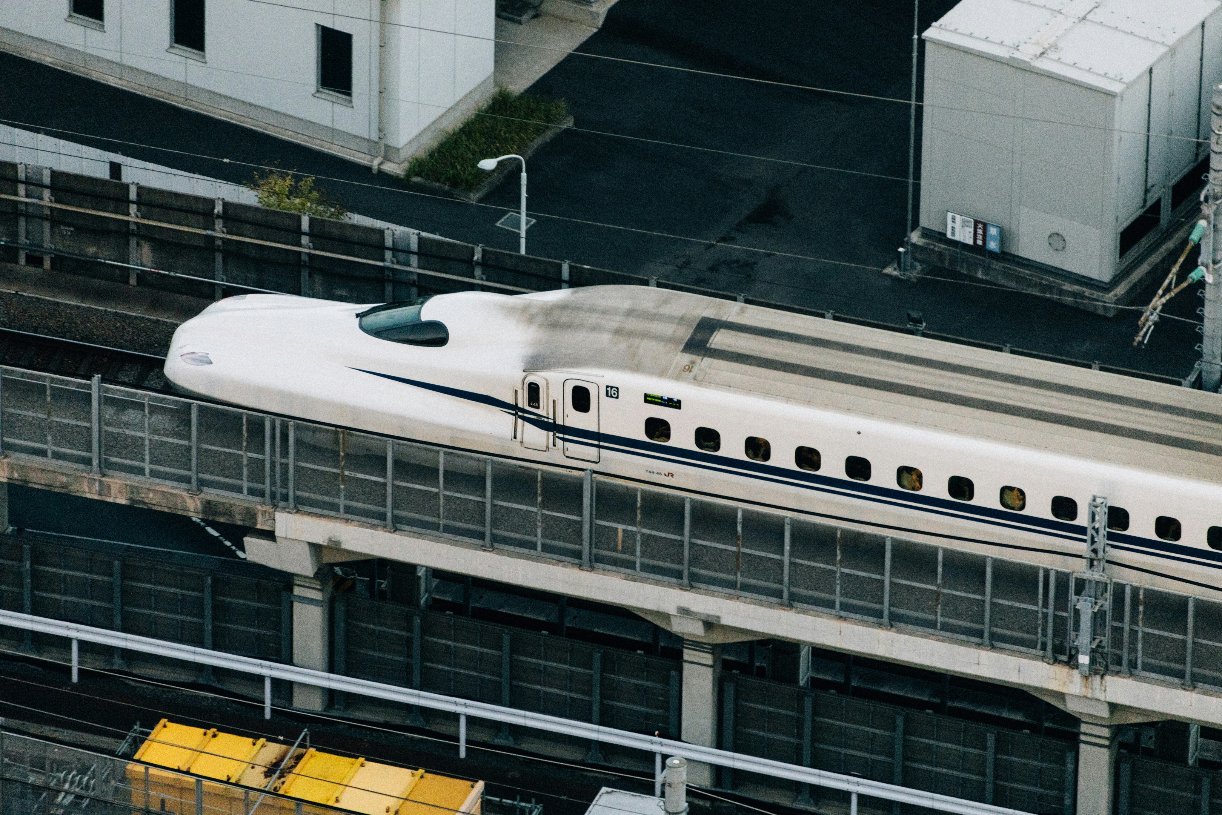 Modern bullet train speeding along tracks near buildings.