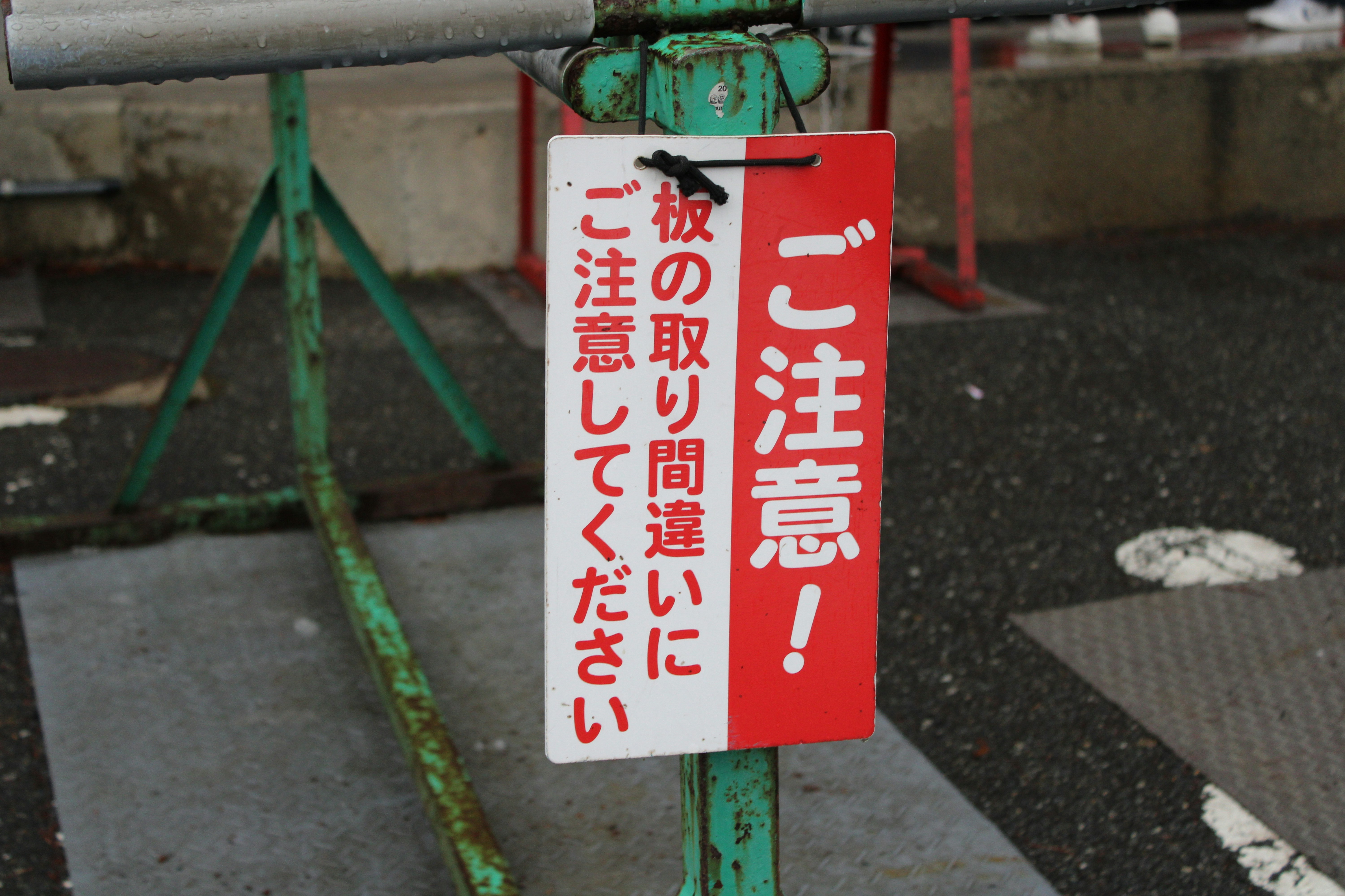 Red safety cone with Japanese 'Watch Your Step' sign on an icy surface