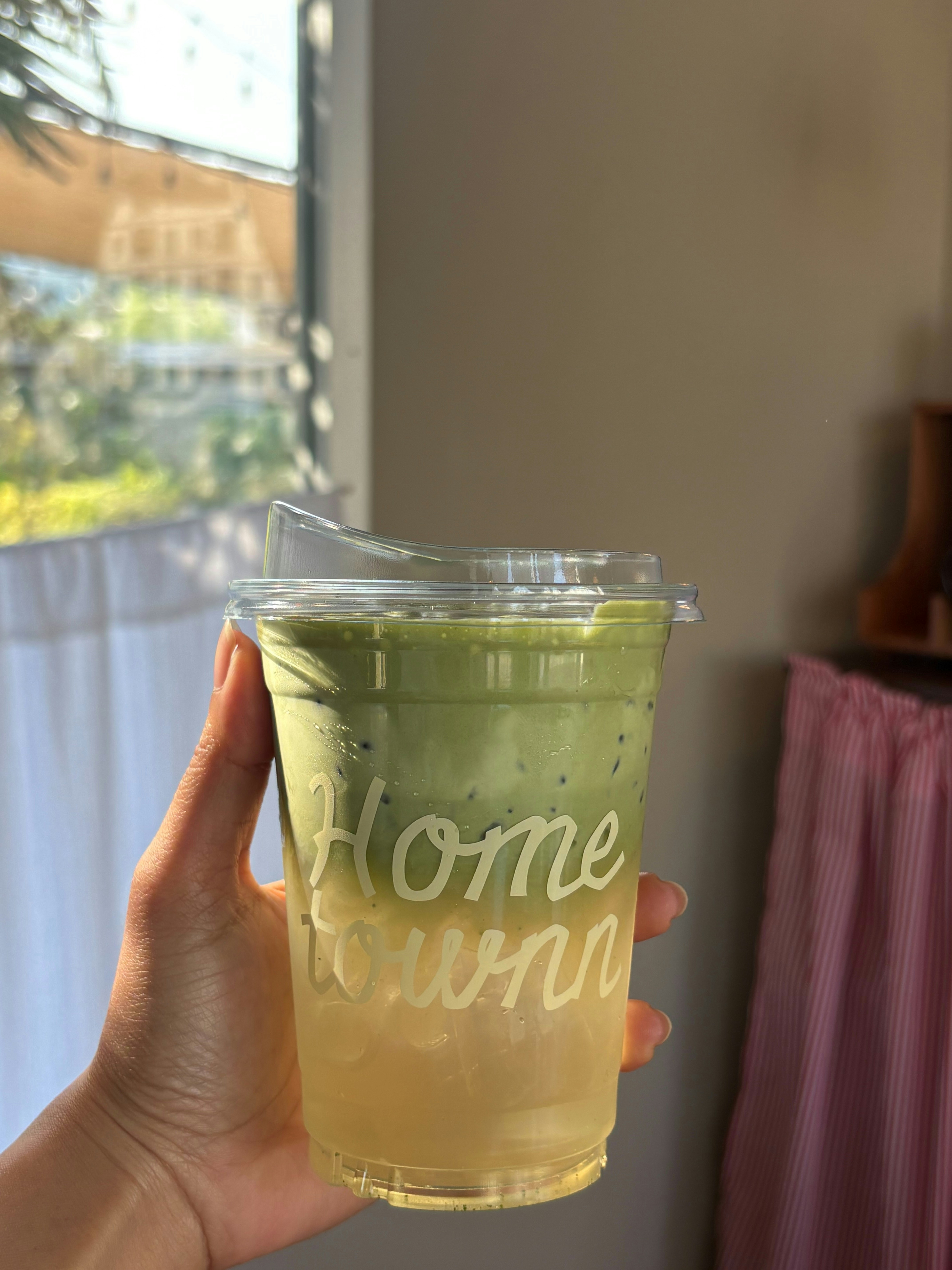 Hand holding a layered green and yellow beverage.