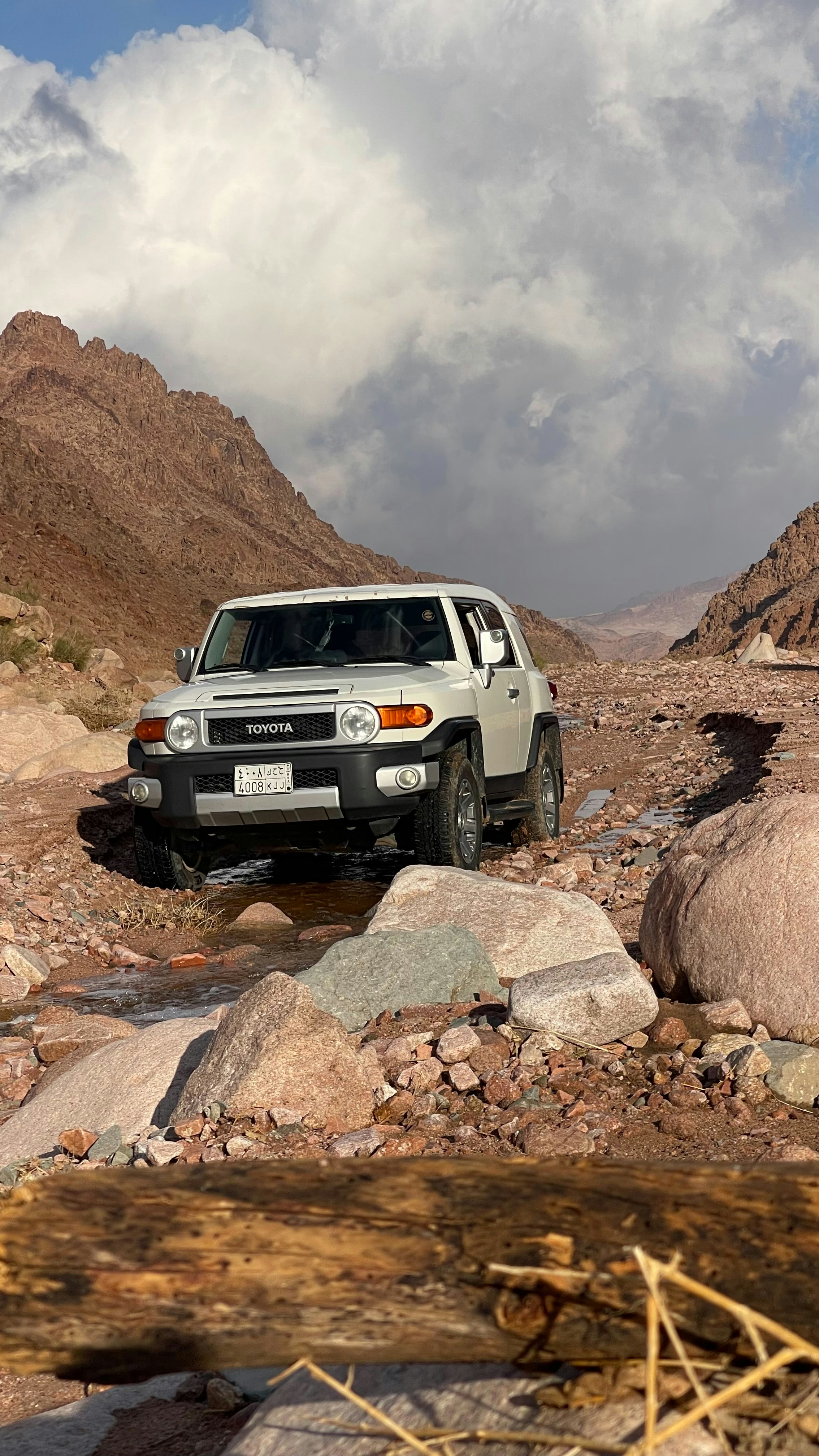 White suv driving through a rocky, dry riverbed.