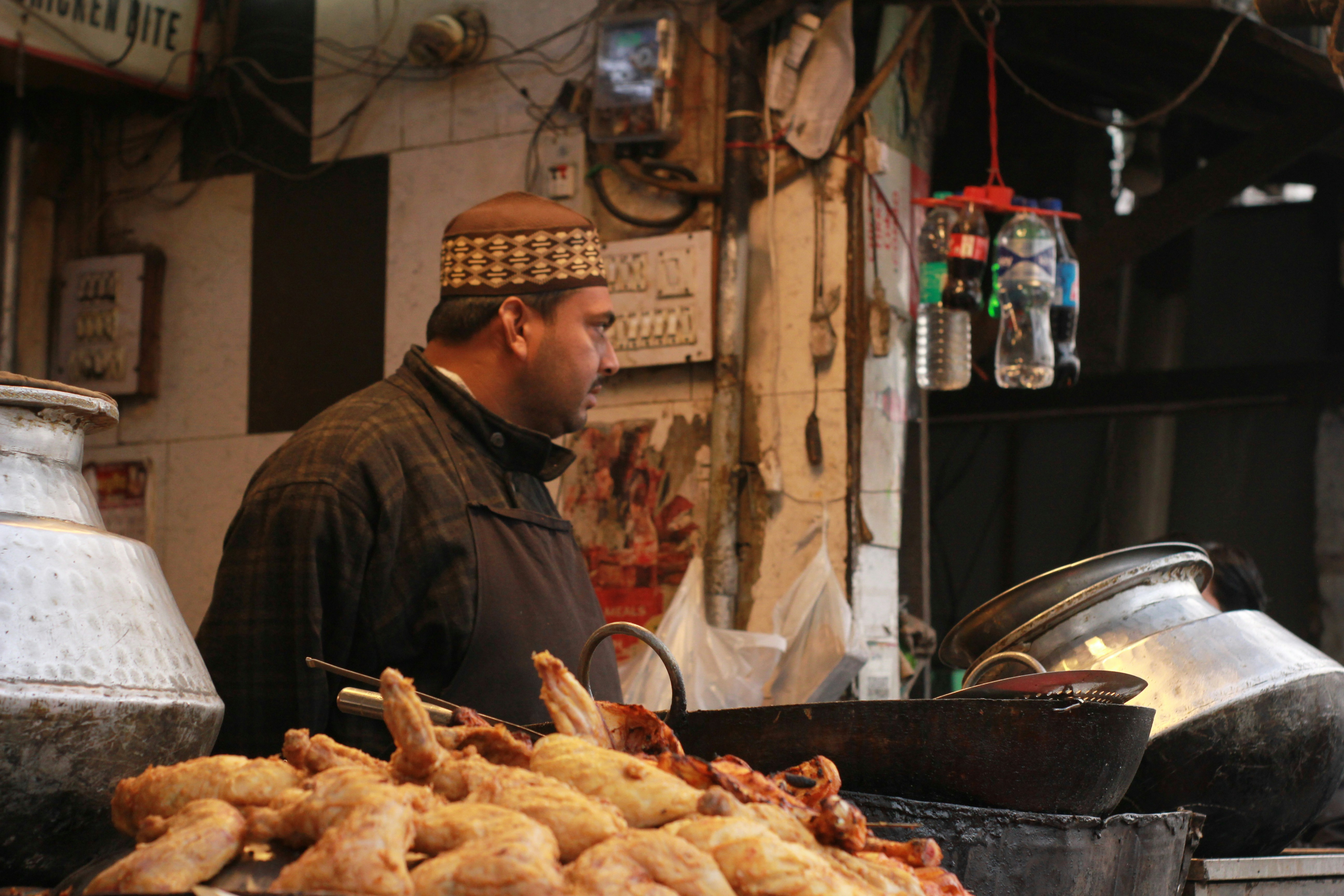Man selling fried chicken at a street food stall.