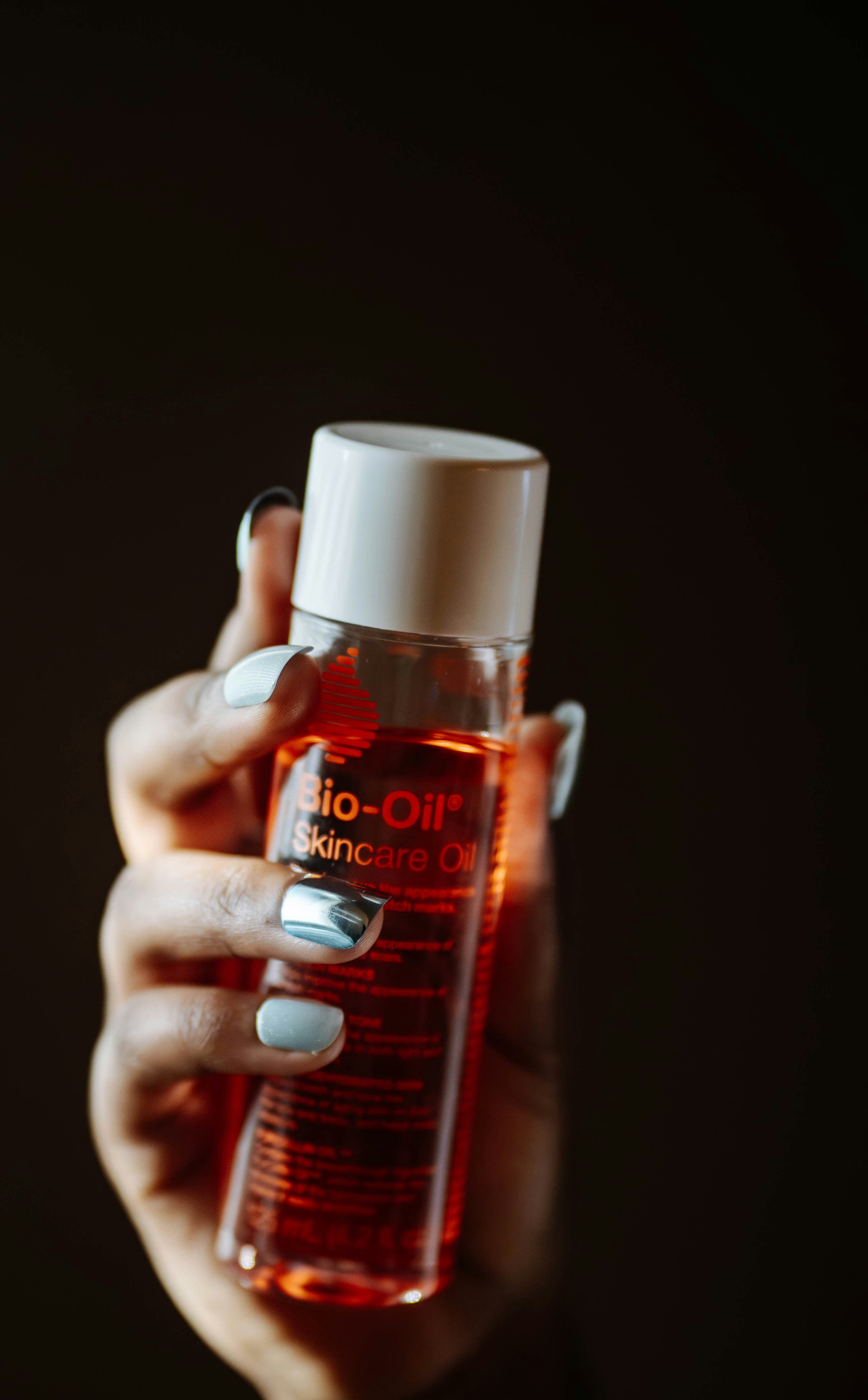 Hand holding a bottle of bio-oil skincare oil.