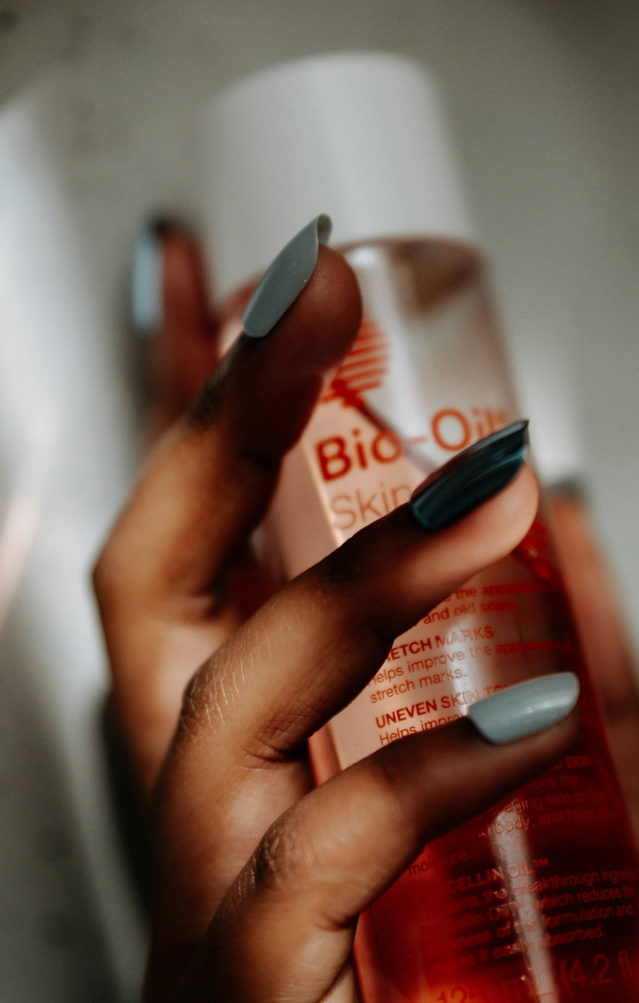 Hand holding a bottle of bio-oil skincare product.