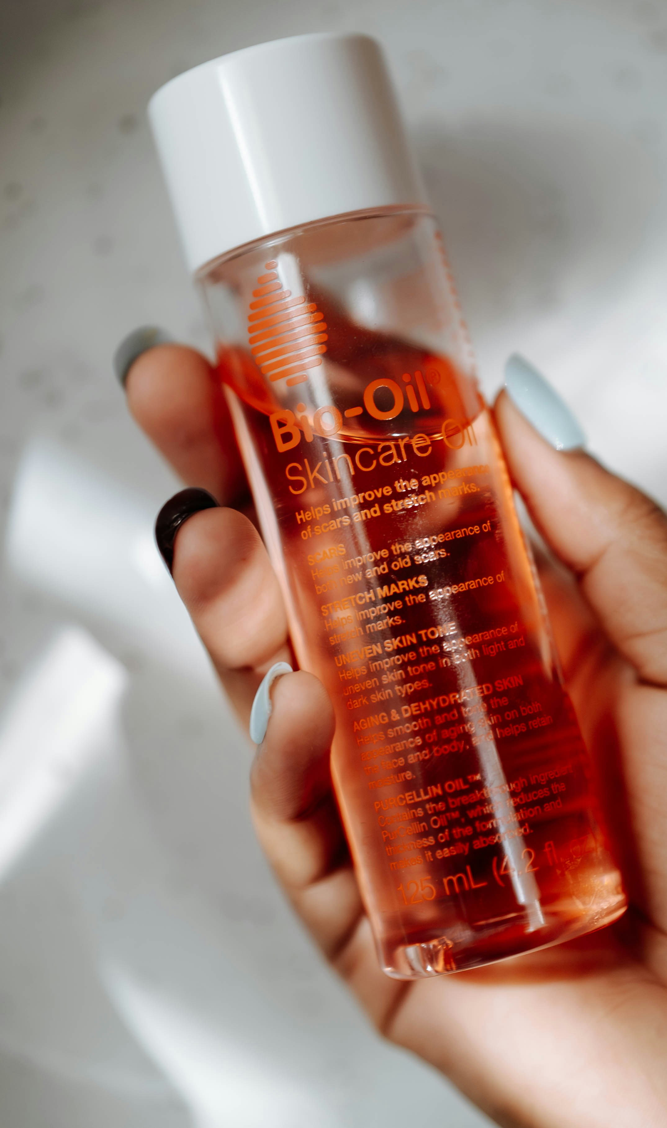 Hand holding a bottle of bio-oil skincare product.