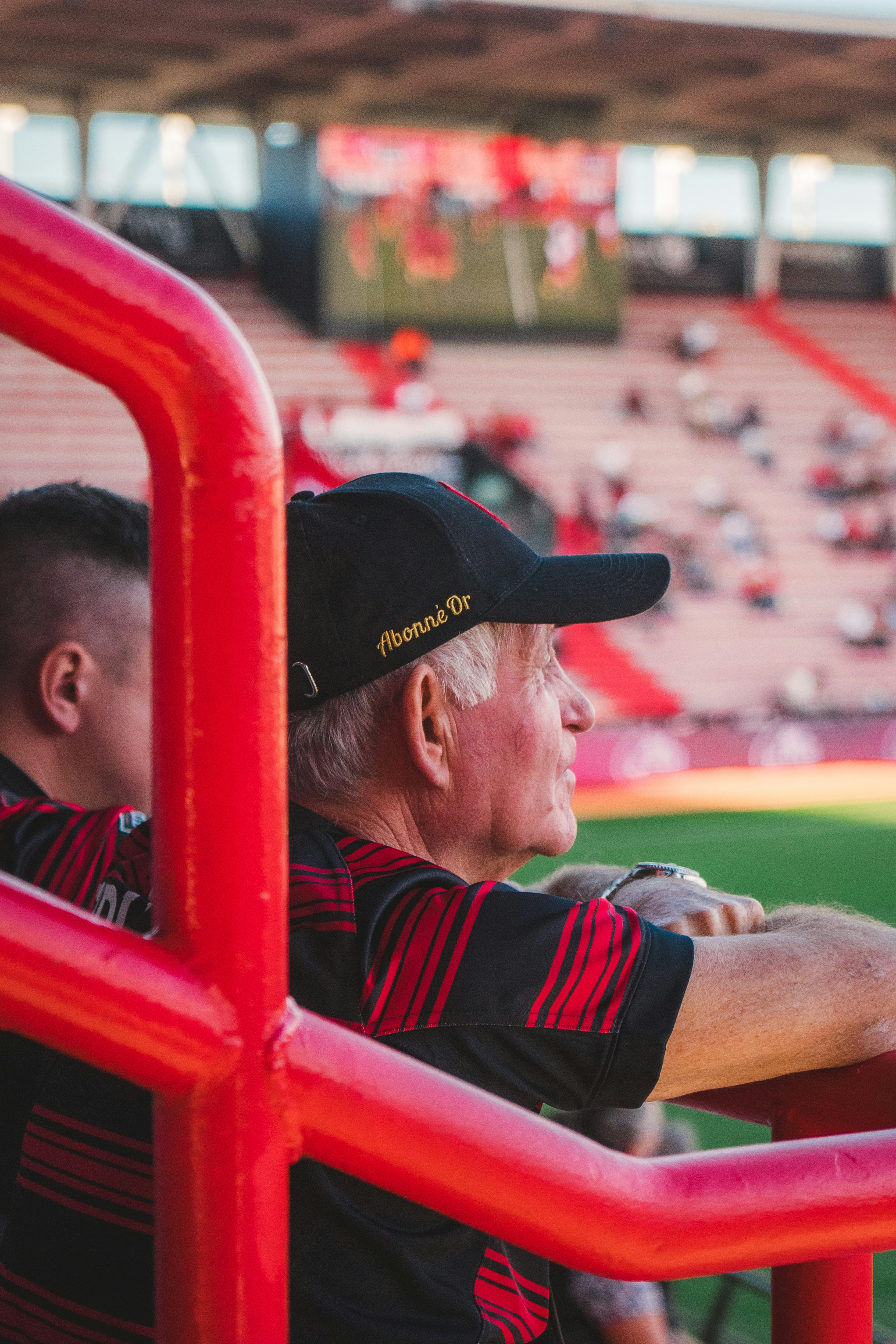Elderly man wearing a baseball cap watches a game.