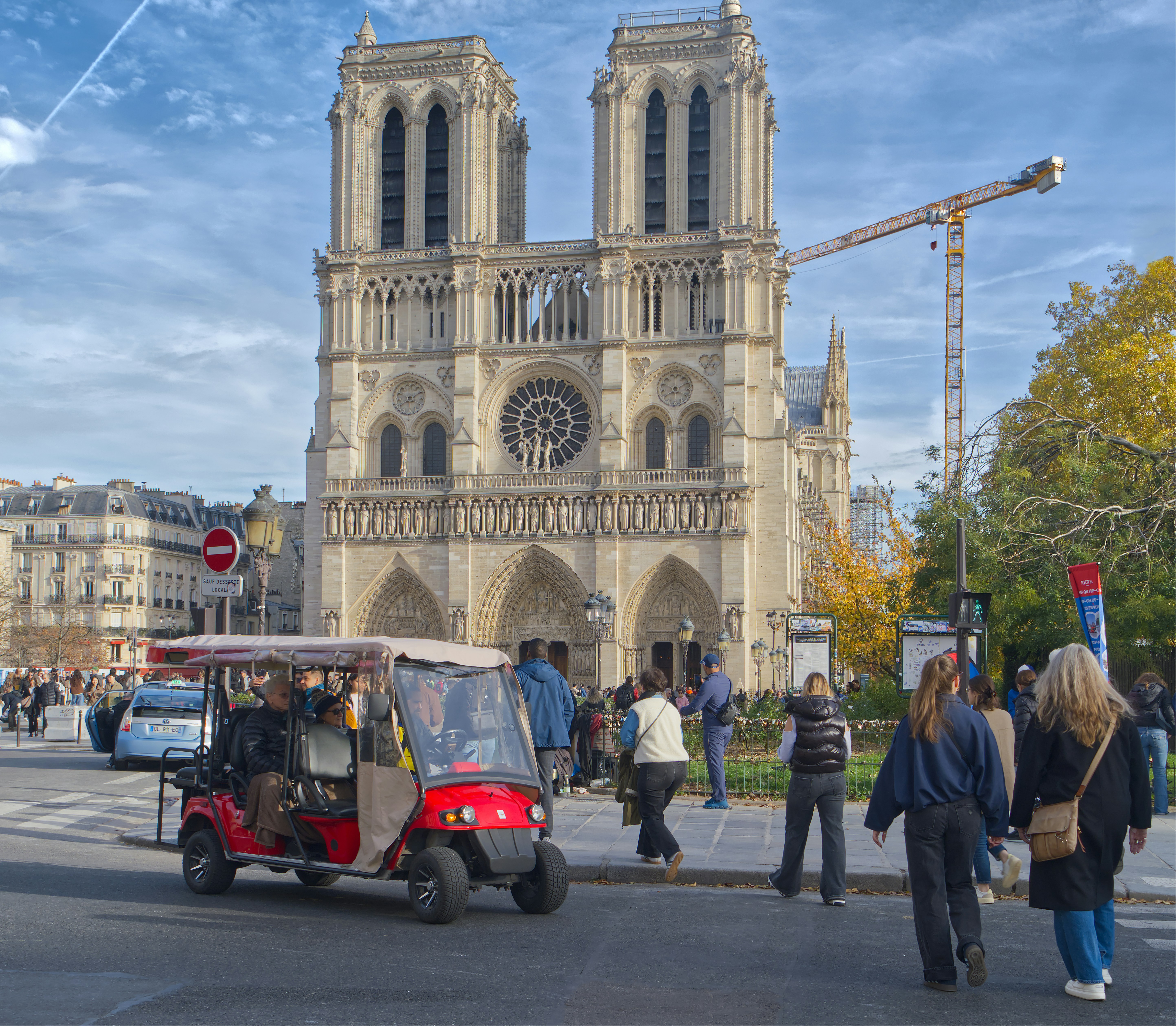 Catedral de Notre Dame com pessoas e um pequeno veículo vermelho.