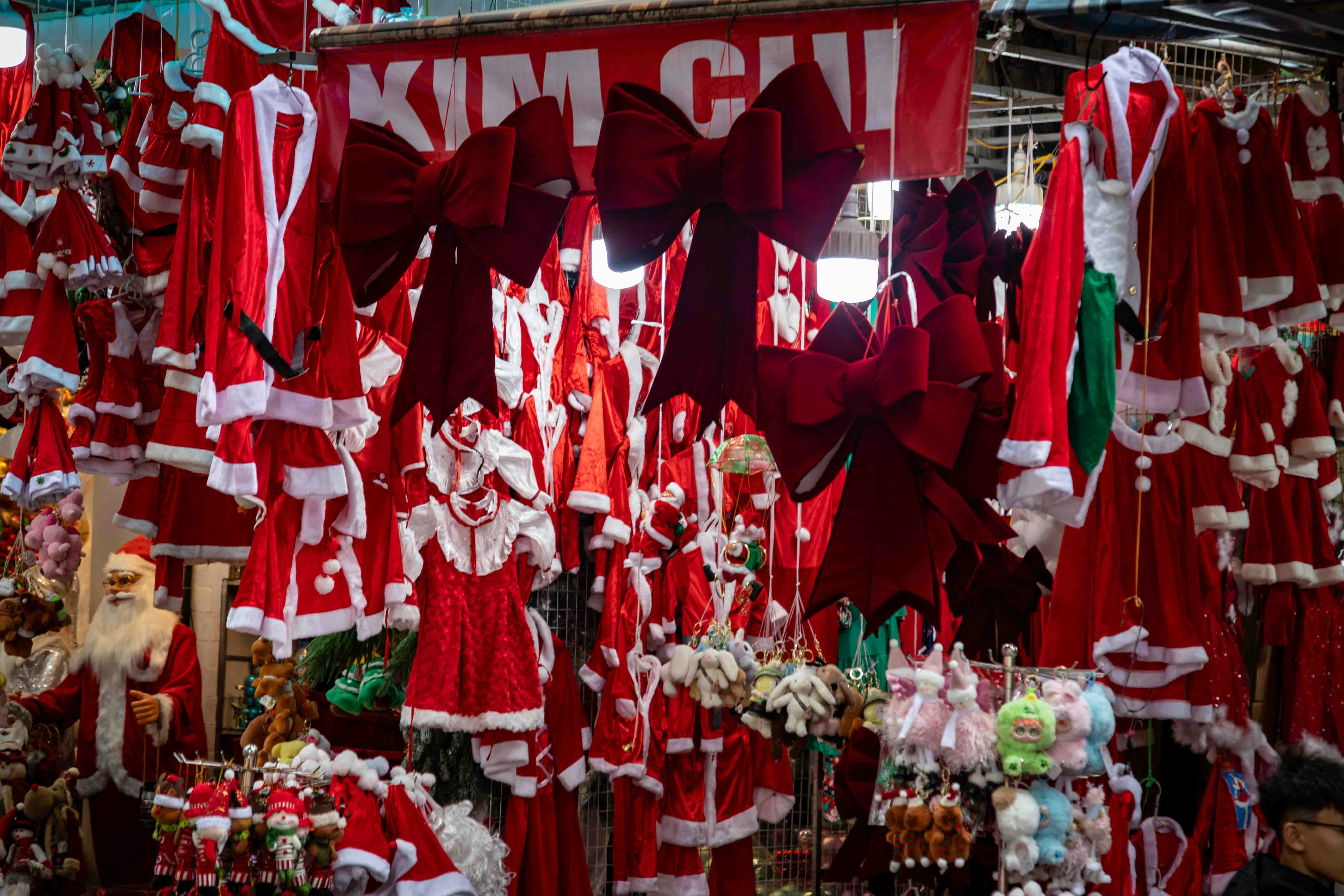 A stall filled with santa claus costumes and christmas costumes.