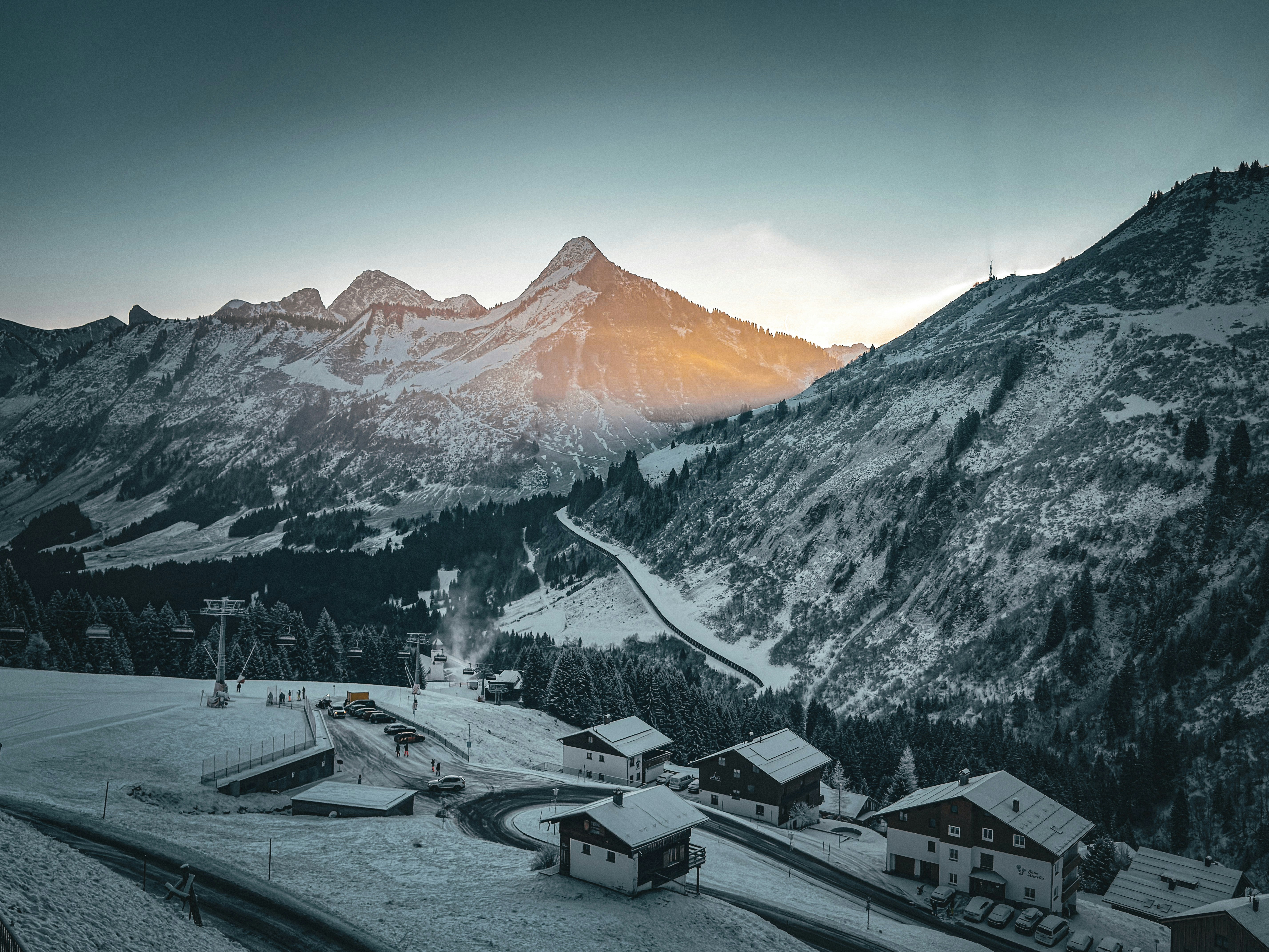 Snowy mountain village with sunlit peak at sunset
