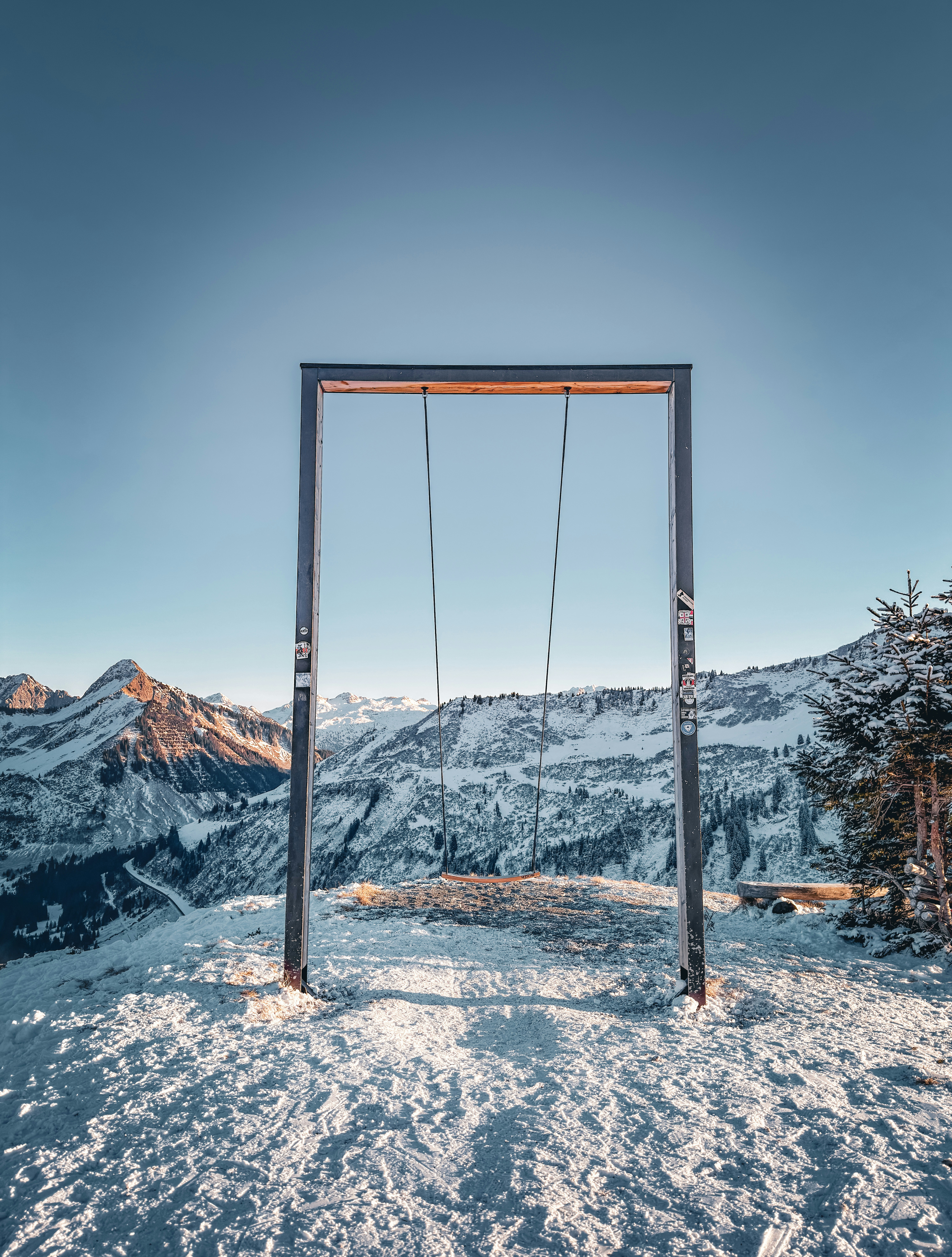 A swing set overlooks a snowy mountain landscape
