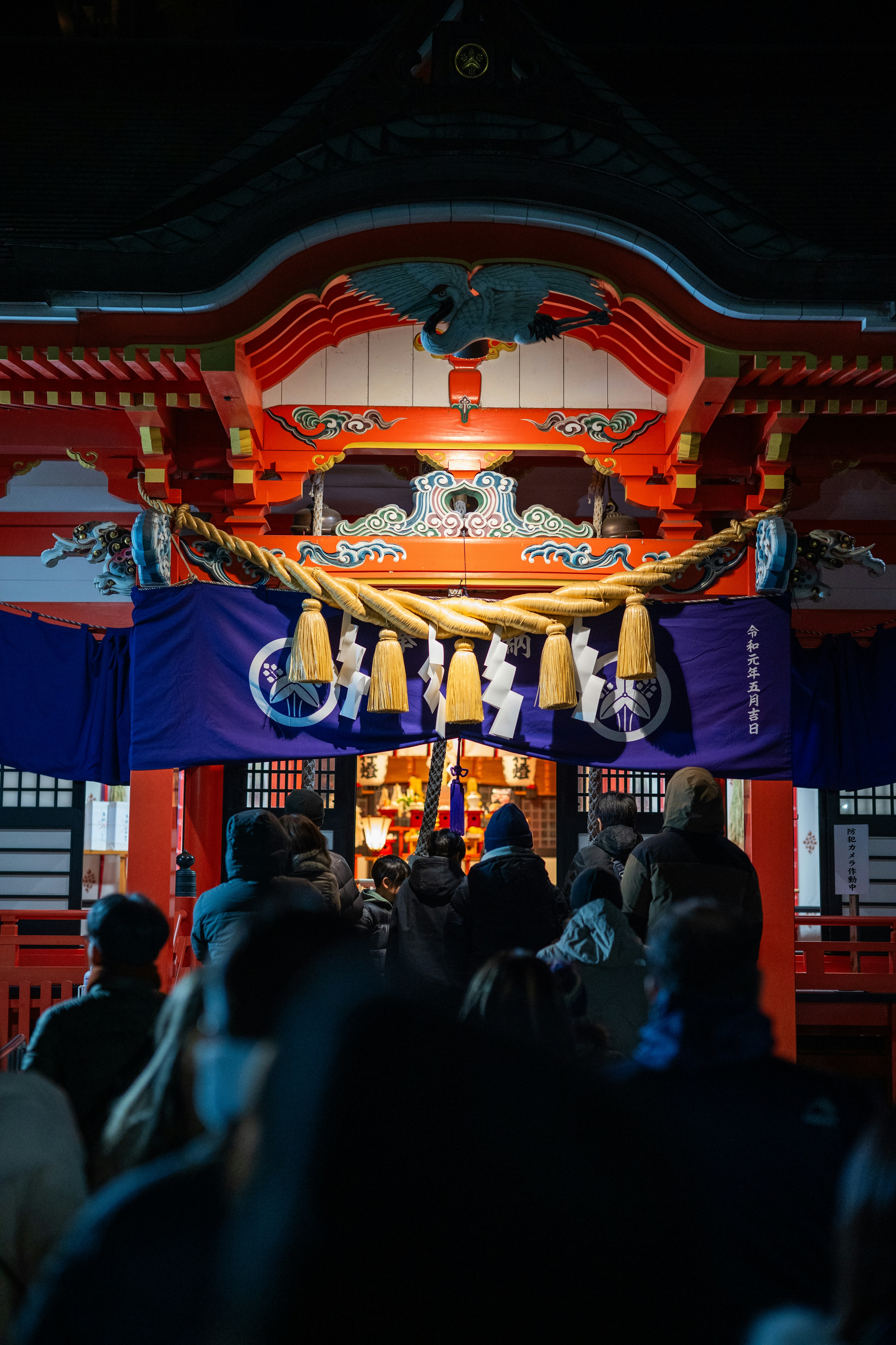 People gathered at a brightly lit japanese shrine