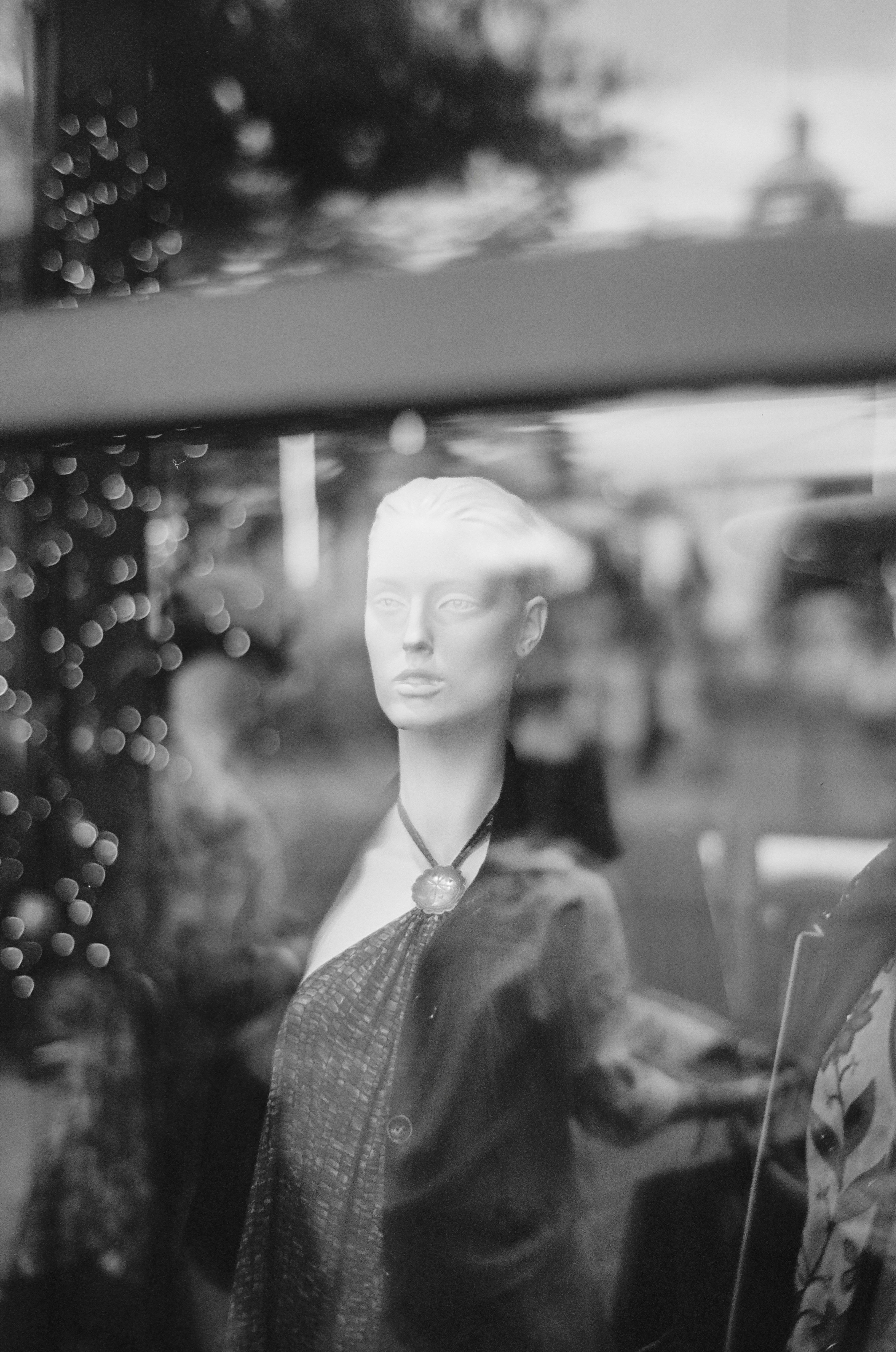 Mannequin in a window display with bokeh lights.