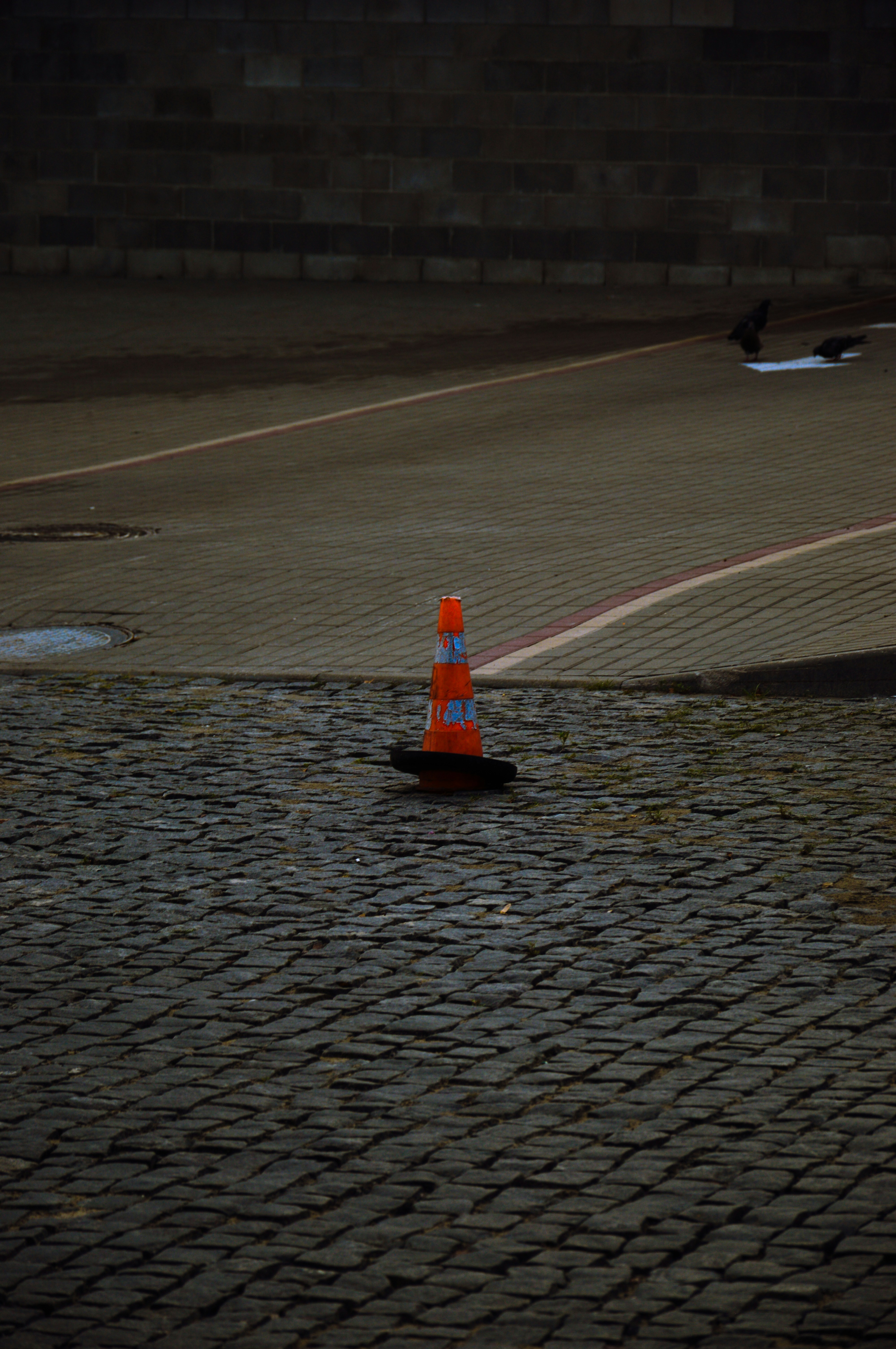 Orange traffic cone on cobblestone street