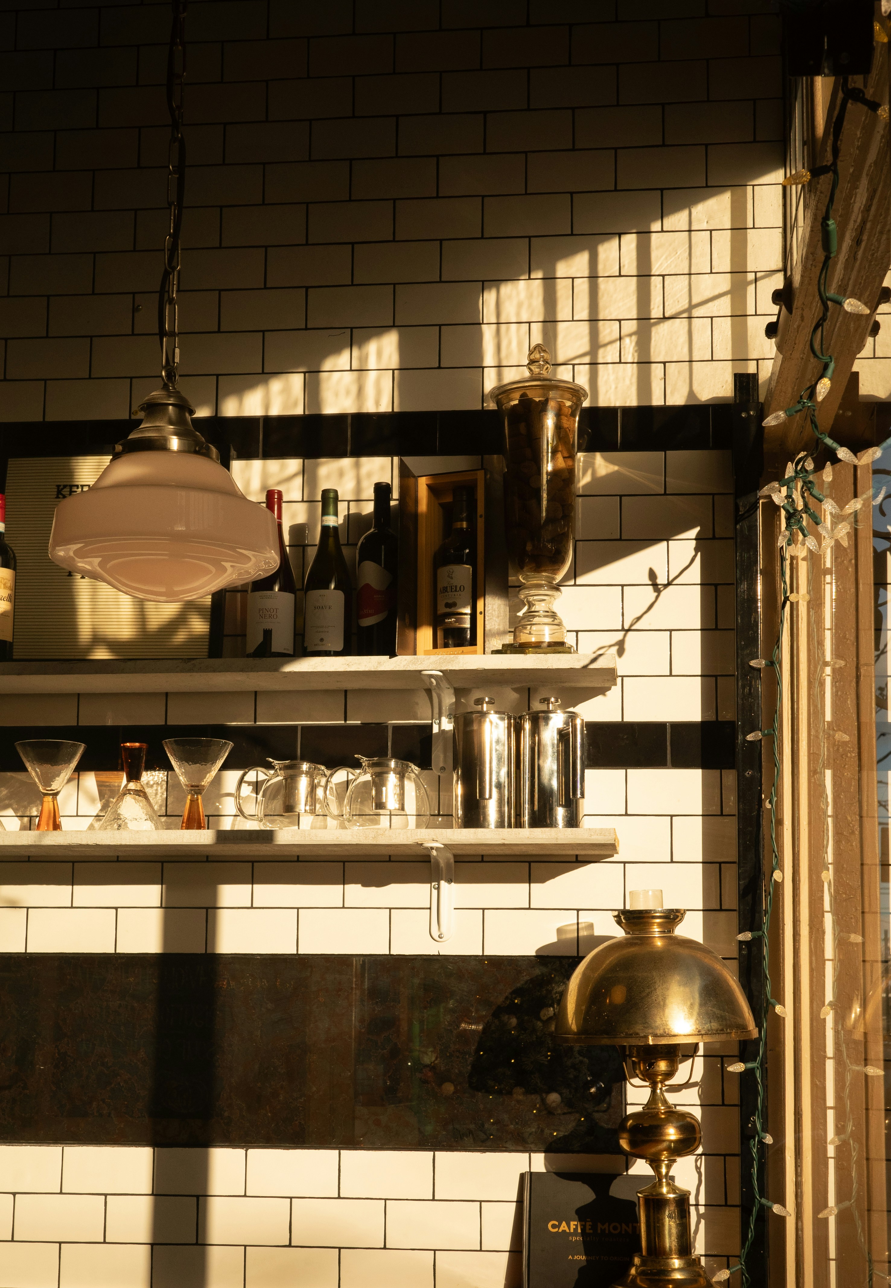 Sunlight streams into a cafe with tiled walls.