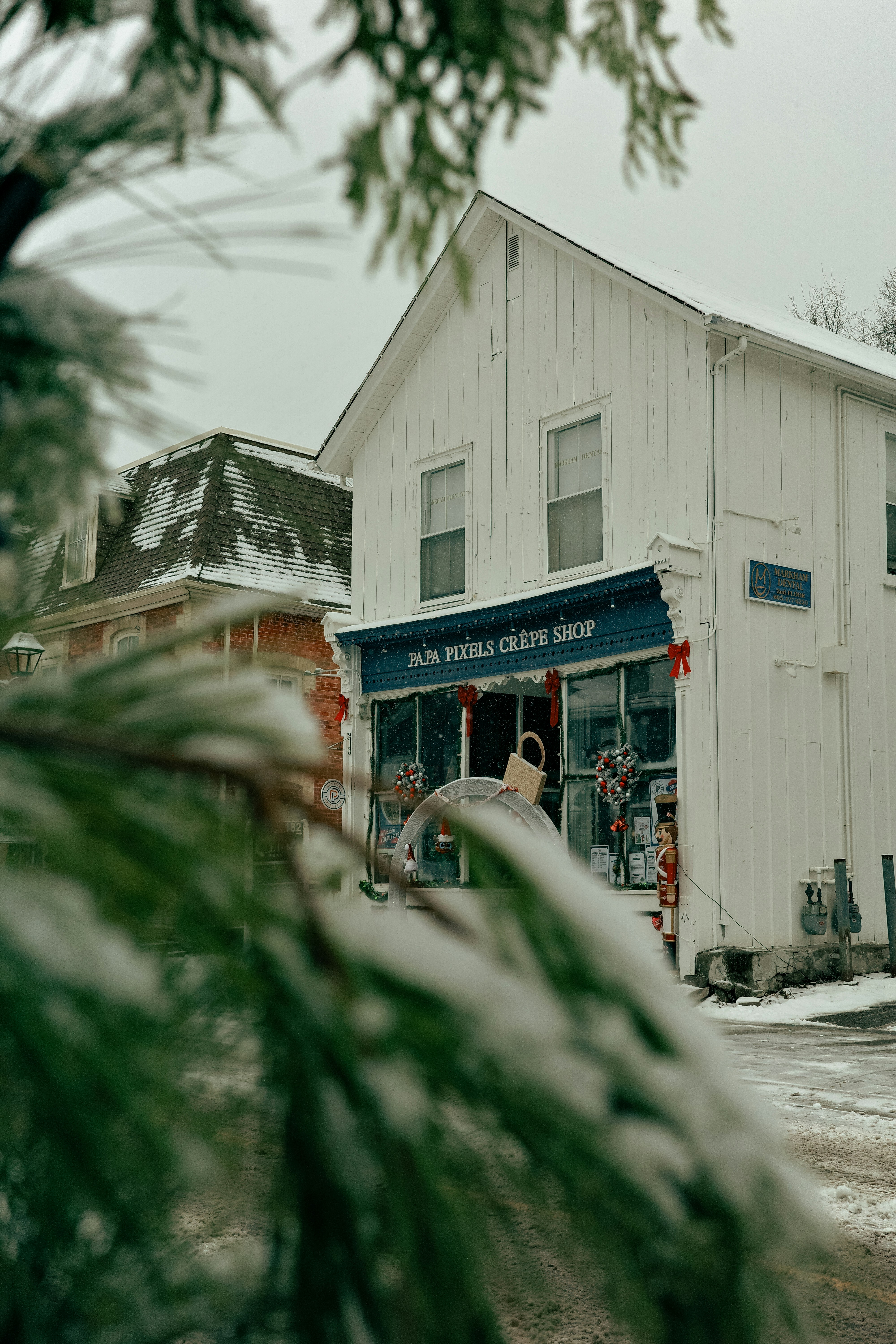 White building with a blue awning and holiday decorations.