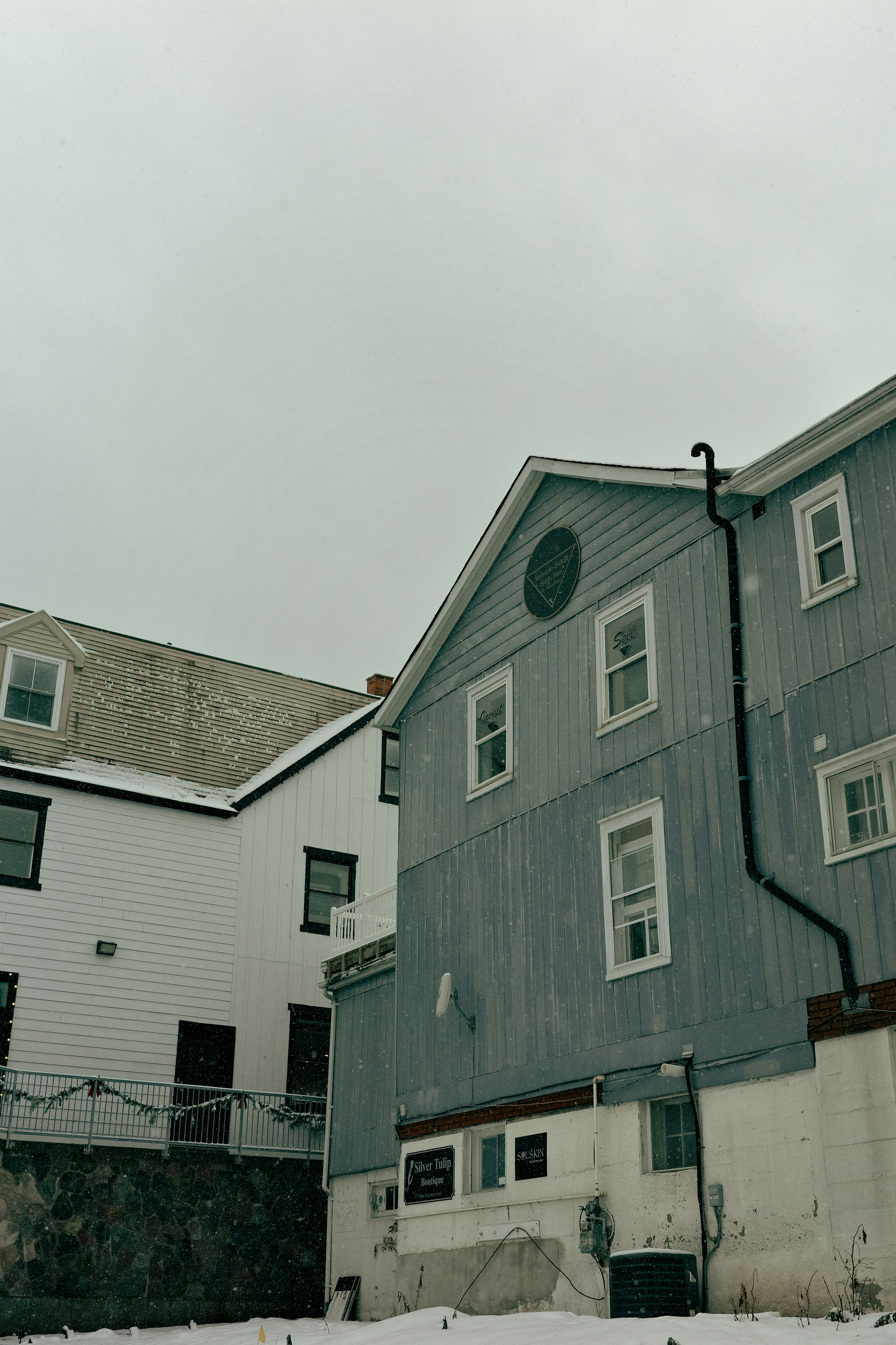 Des bâtiments avec de la neige tombant par une journée nuageux.