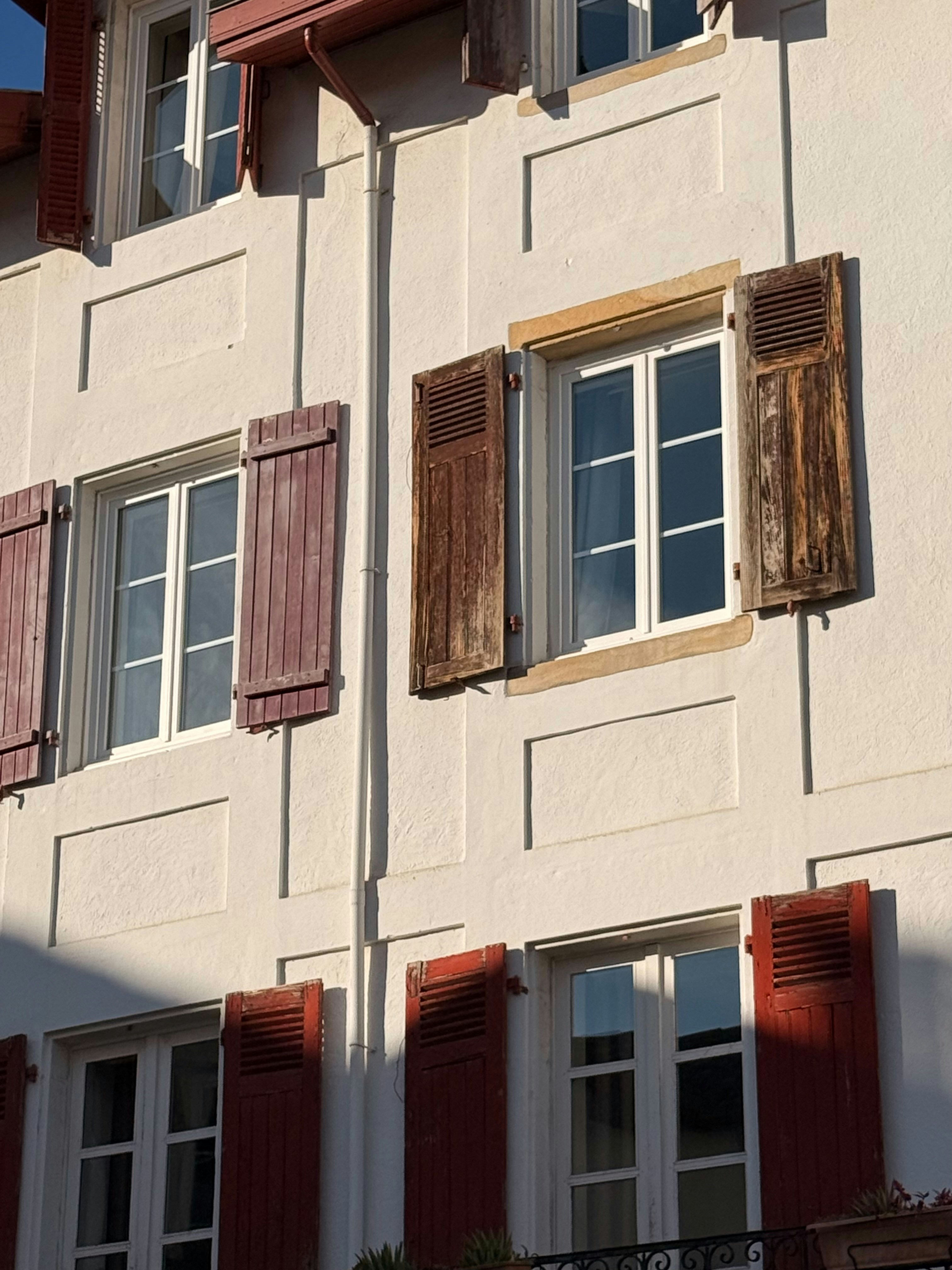 Building facade with open and closed wooden shutters.