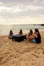 Four friends sitting around a fire pit on the beach