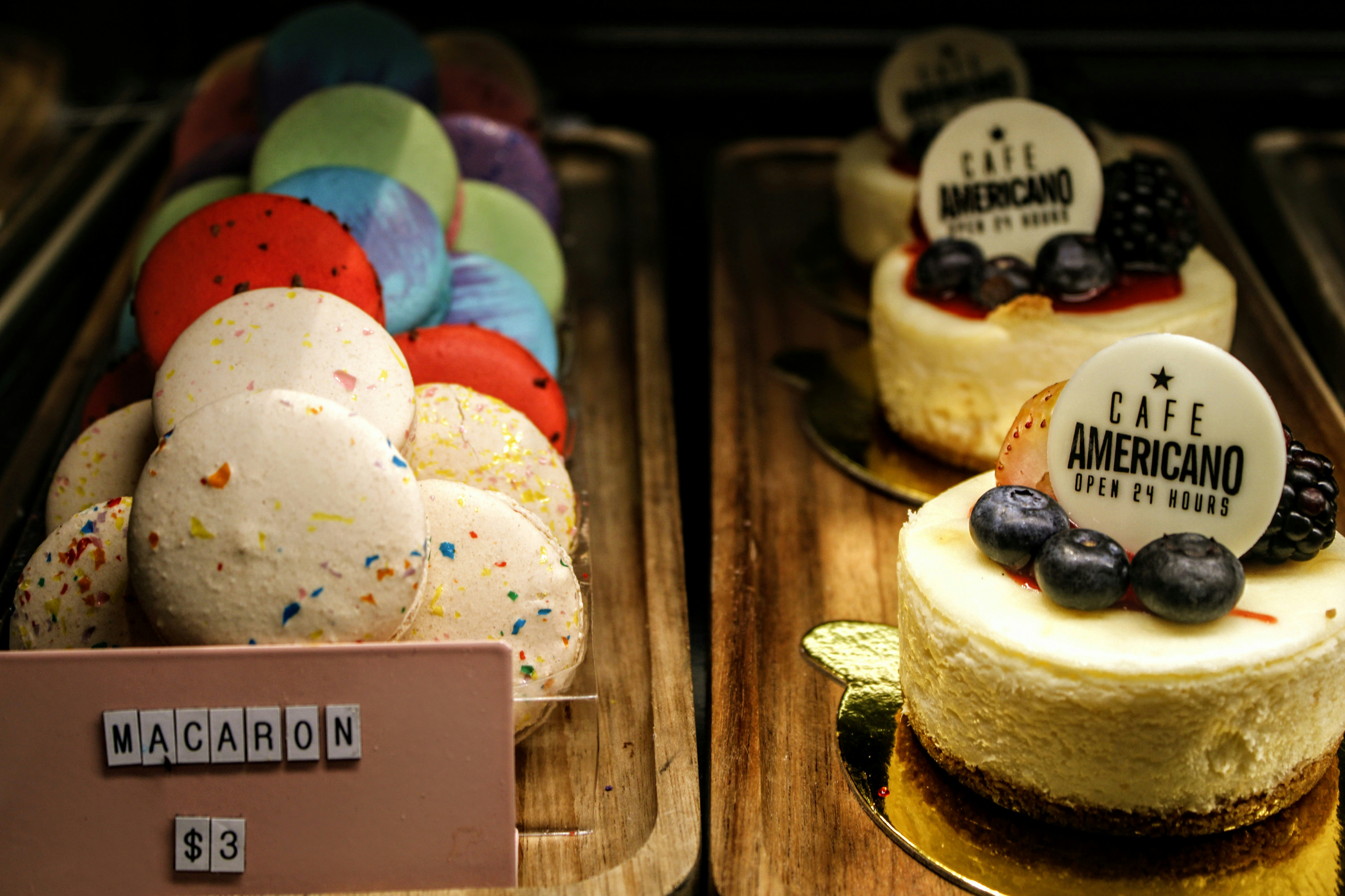 Colorful macarons and cheesecakes displayed at a cafe.
