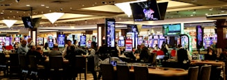People playing slot machines in a brightly lit casino.