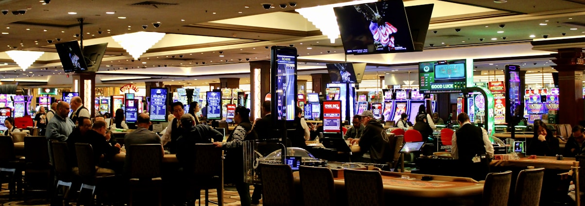 People playing slot machines in a brightly lit casino.