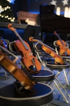 Several violins rest on chairs in a dimly lit room.